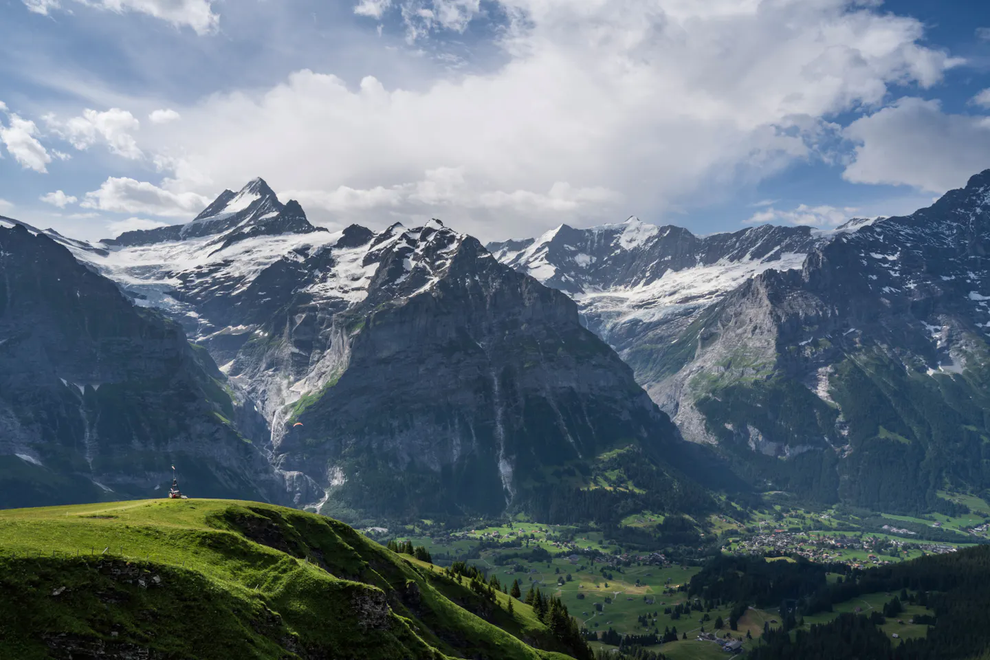 Snow-capped peaks of the Jungfrau region above green alpine meadows and a valley of scattered villages