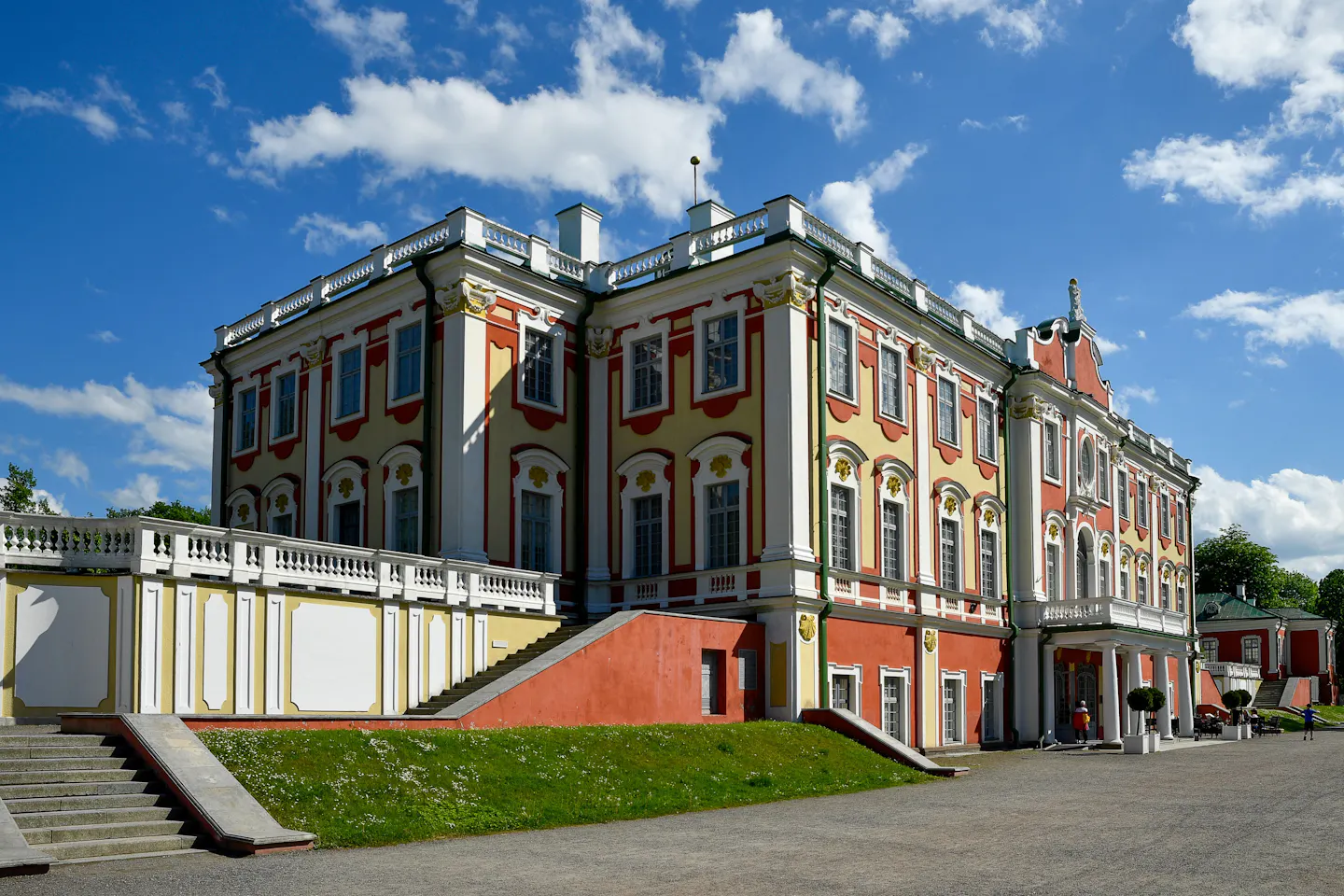 The pink and yellow baroque facade of Kadriorg Palace in Tallinn under a bright cloudy sky