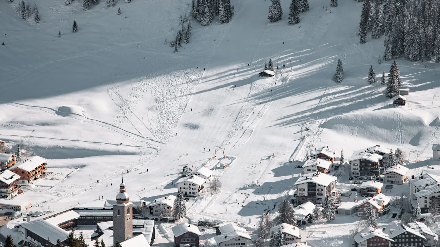 Lech am Arlberg’s snow-covered village and church beneath sunny ski slopes