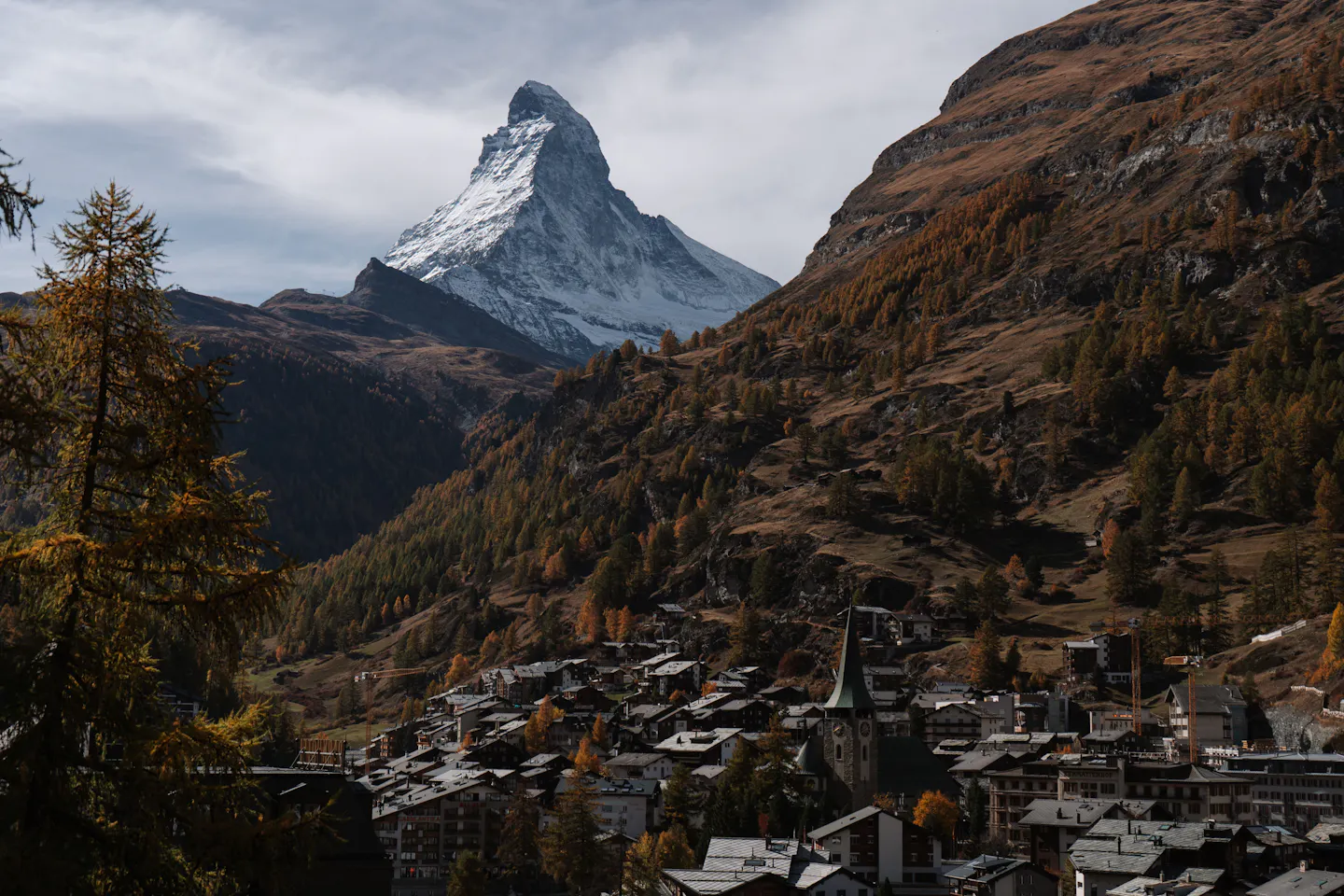 The snow-streaked pyramid of the Matterhorn above Zermatt and golden autumn larches