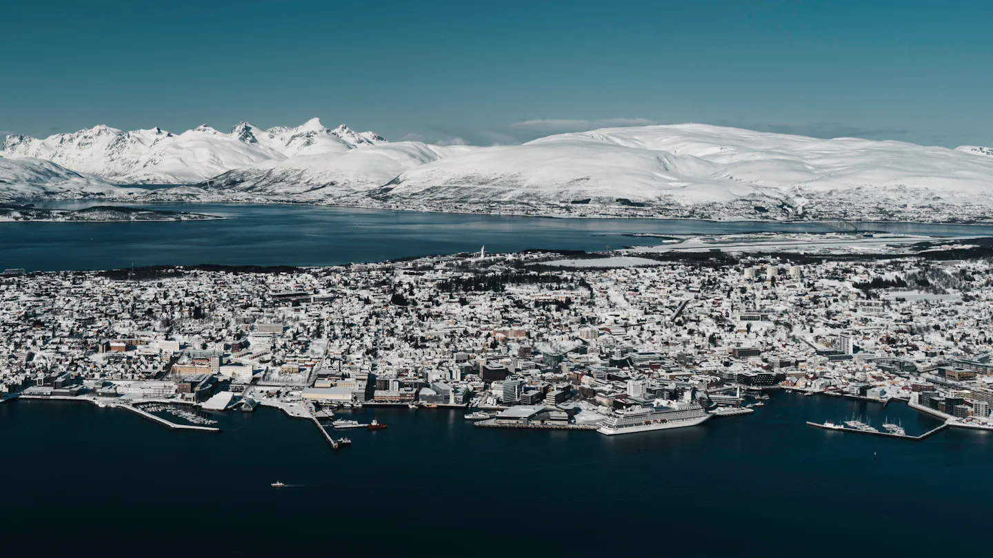 Snow-covered Tromso on its island between the fjord and white Arctic mountains
