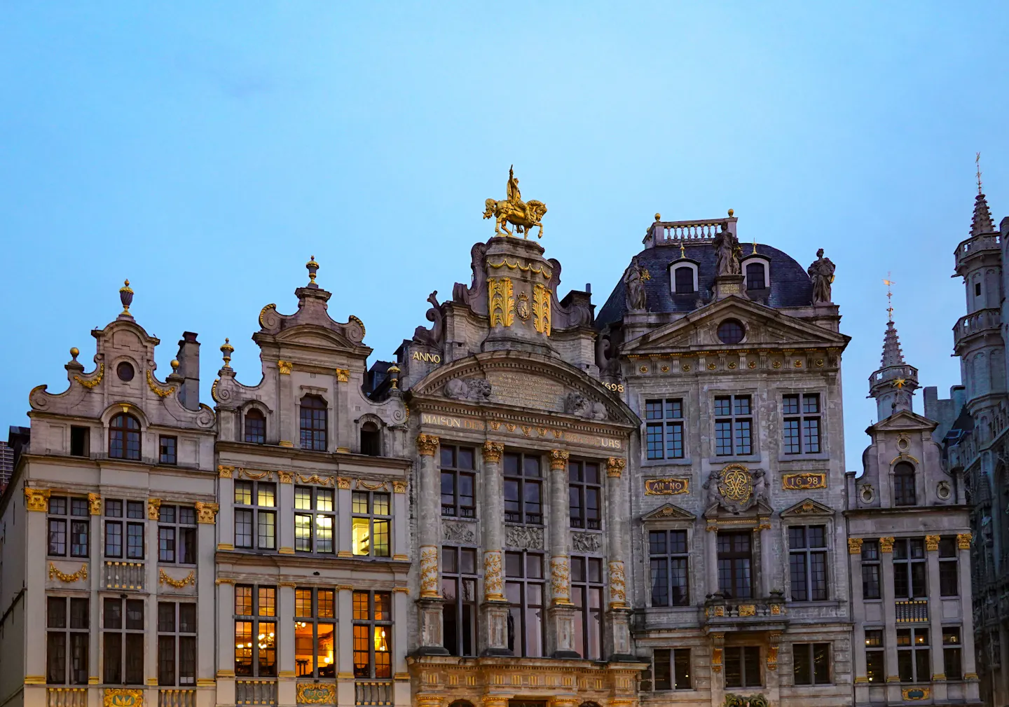 The gilded guild houses of the Grand Place in Brussels lit against a deep blue evening sky