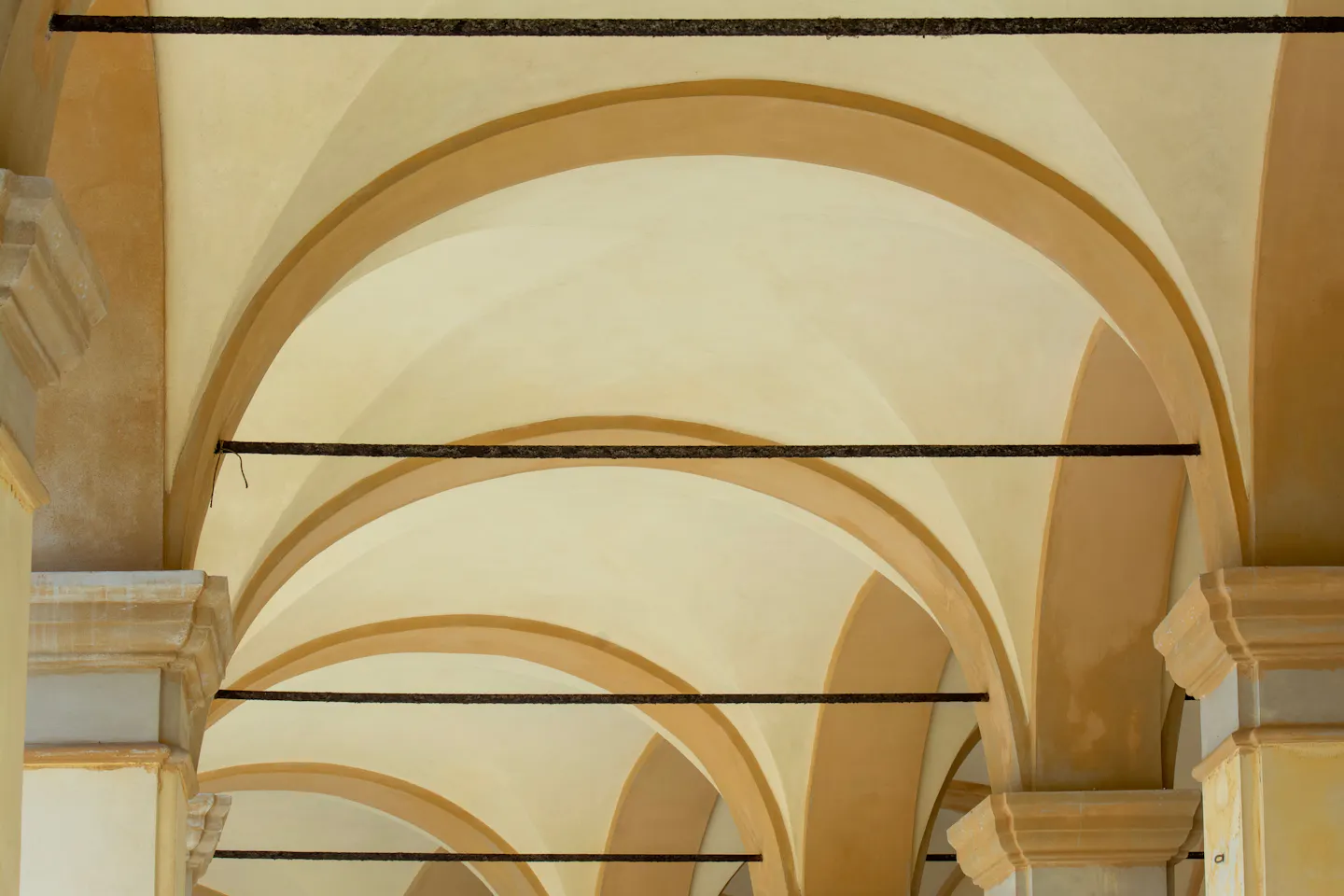 The pale ochre vaults of a Bologna portico receding down a street