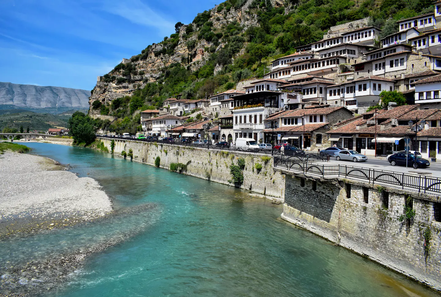 Ottoman houses stacked on a hillside above a turquoise river in Albania