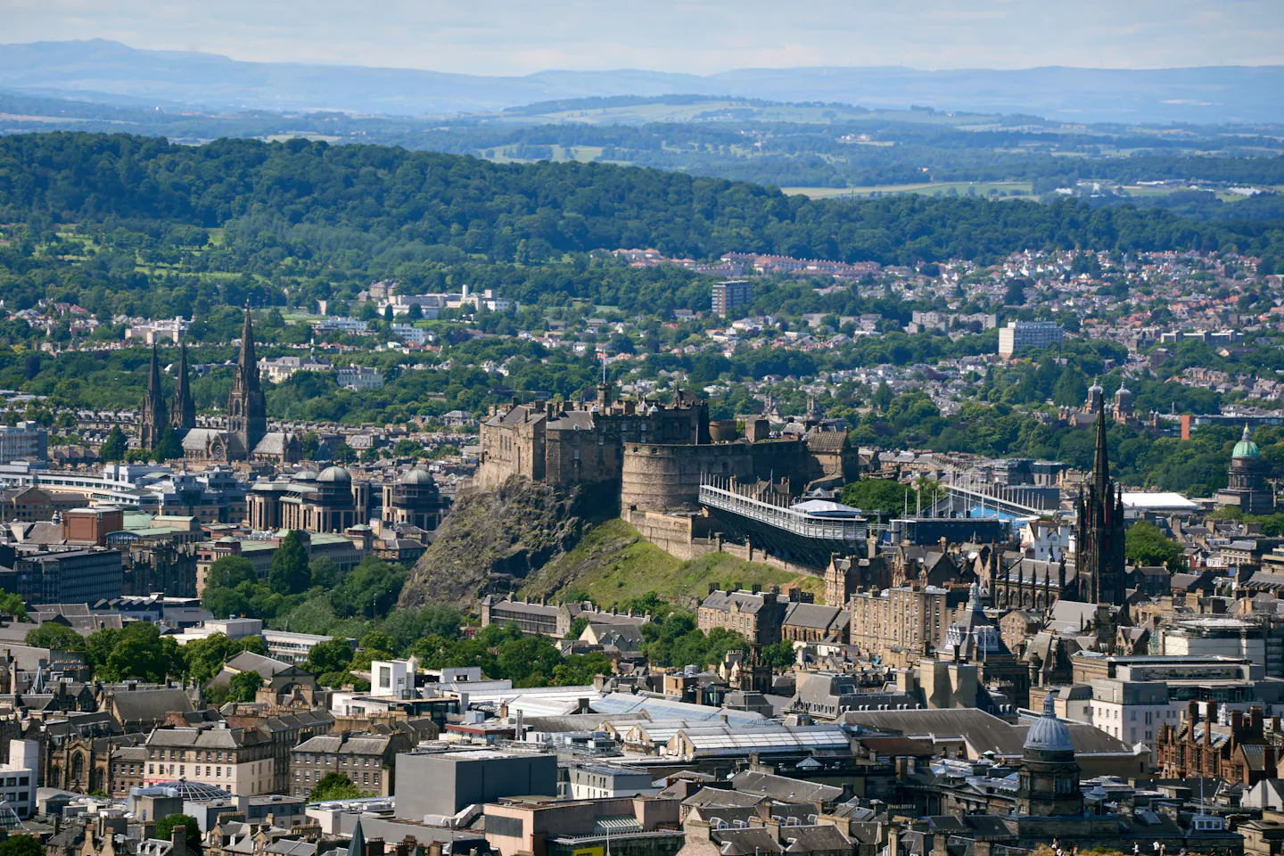 Edinburgh Castle on its volcanic rock above the city, with green hills and the Firth of Forth beyond