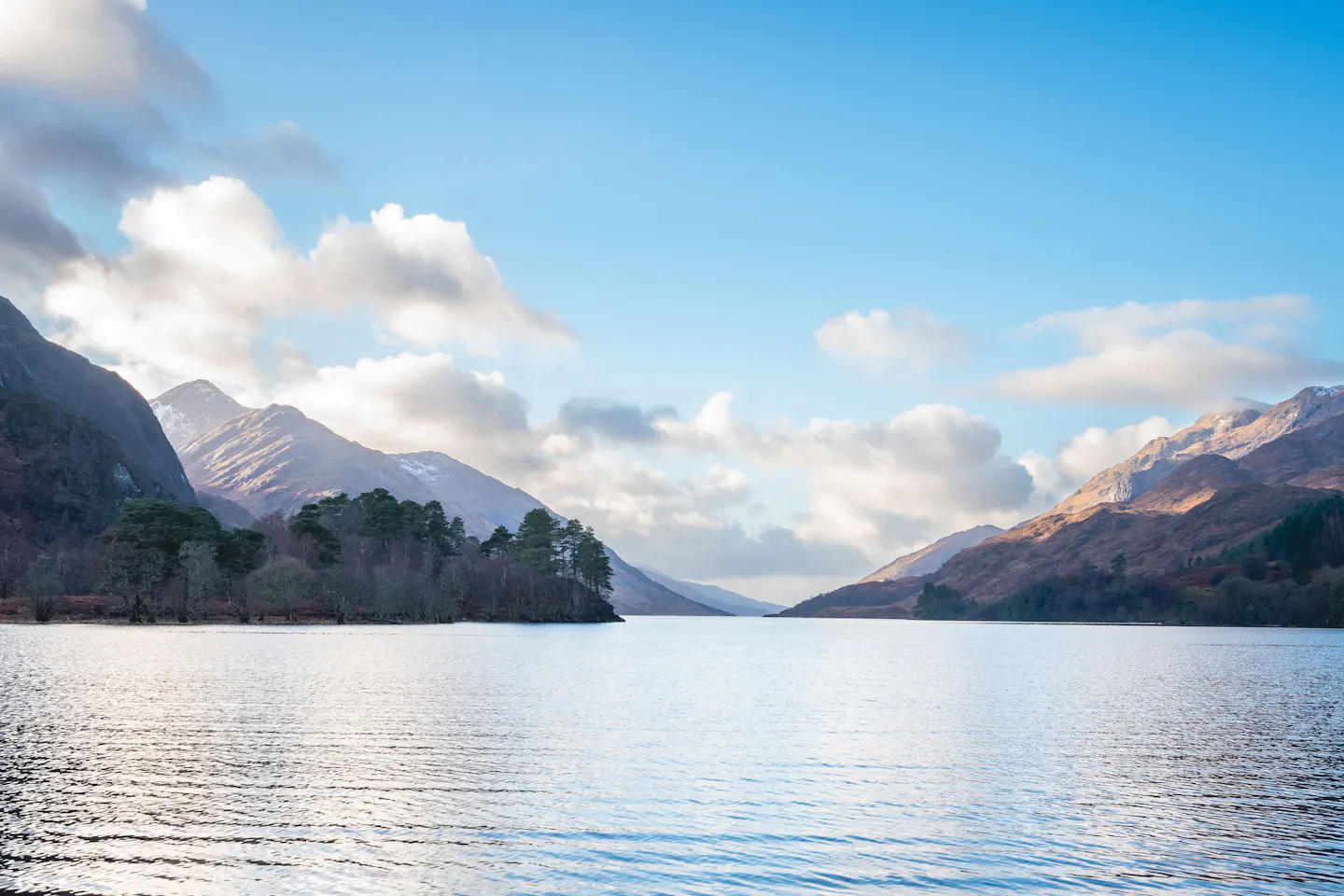 Sunlit mountains rising above the still water of Loch Shiel in the Scottish Highlands