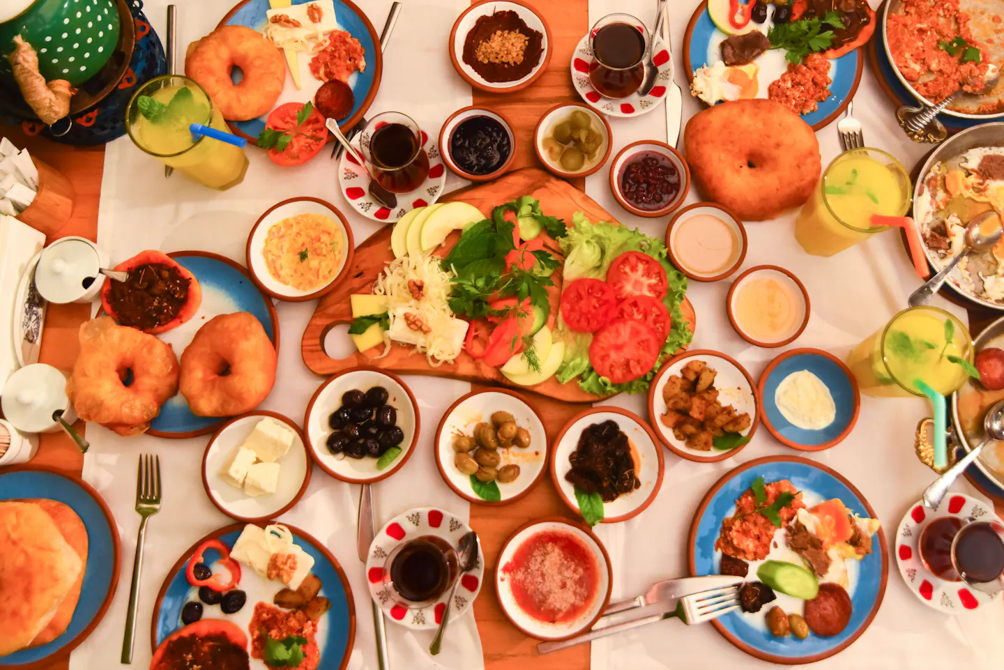 A Turkish breakfast seen from above with cheeses, olives, jams, eggs, breads and tulip glasses of tea