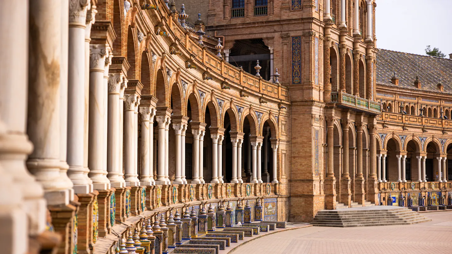 The curving tiled arcade and marble columns of the Plaza de España in Seville in warm light