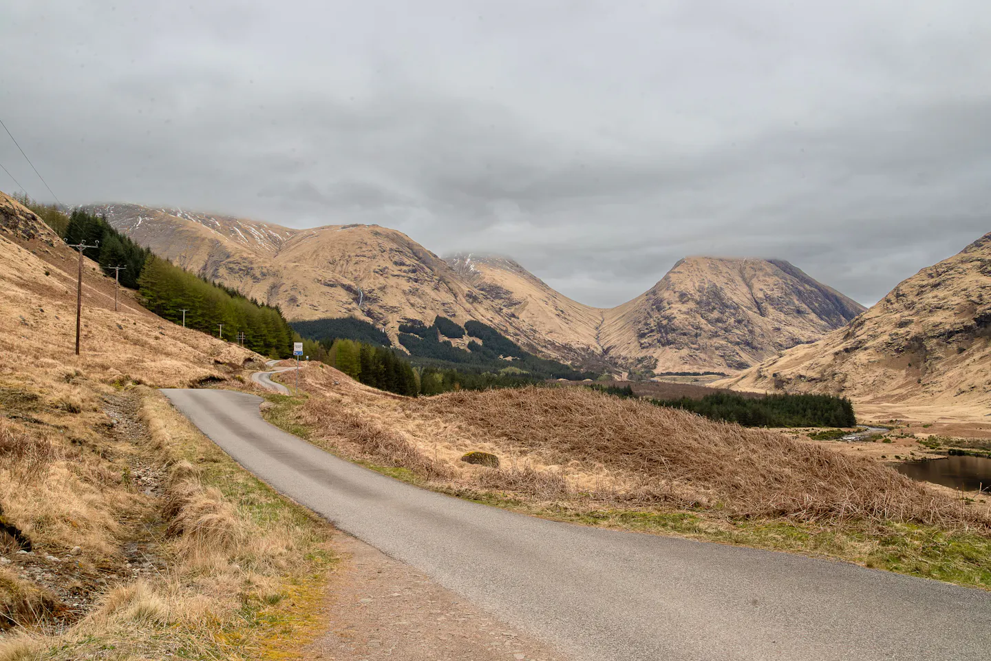 A winding road through the brown glens and rugged mountains of the Scottish Highlands
