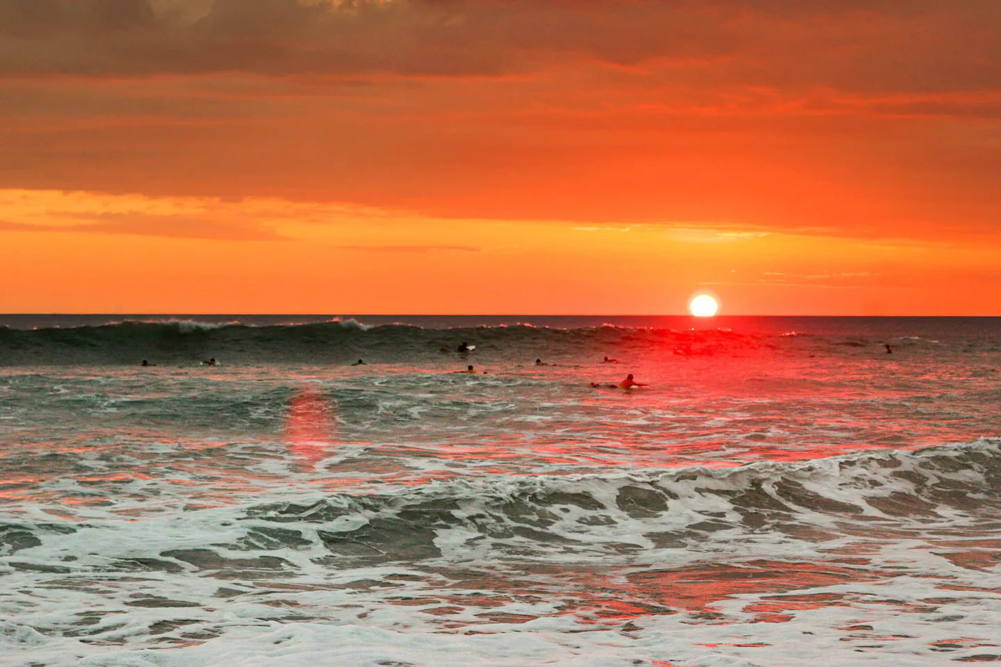 Guanacaste beach in Costa Rica at sunset, with surfers in the Pacific waves
