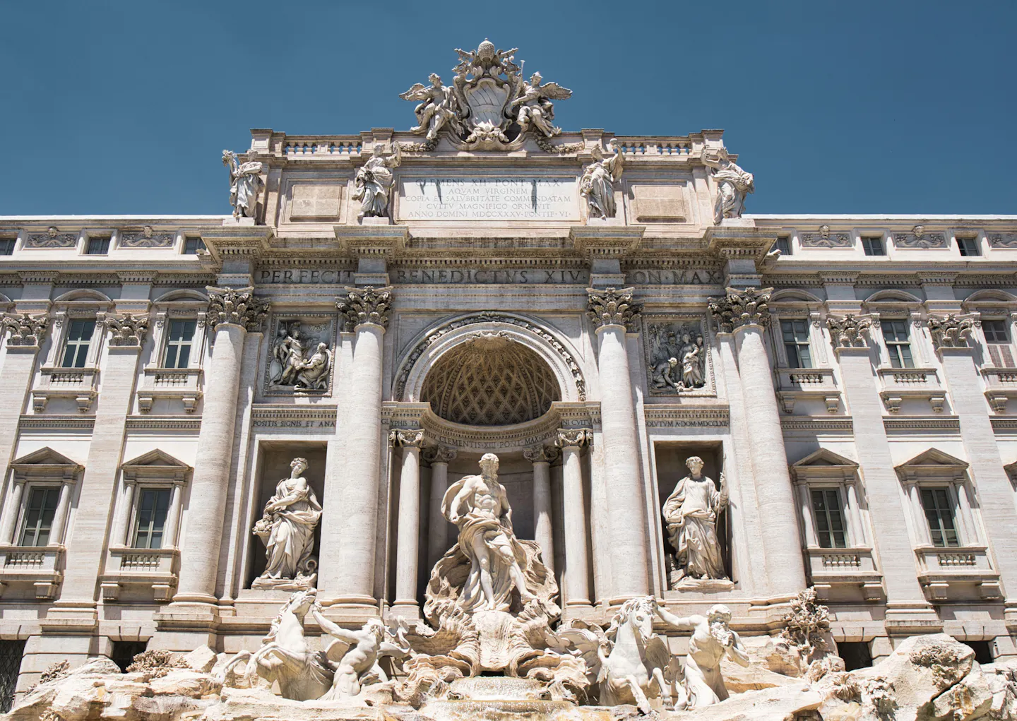The Trevi Fountain in Rome under a deep blue sky: Oceanus in the central niche, the sea-horses and travertine rocks below and the palazzo facade with its statues above