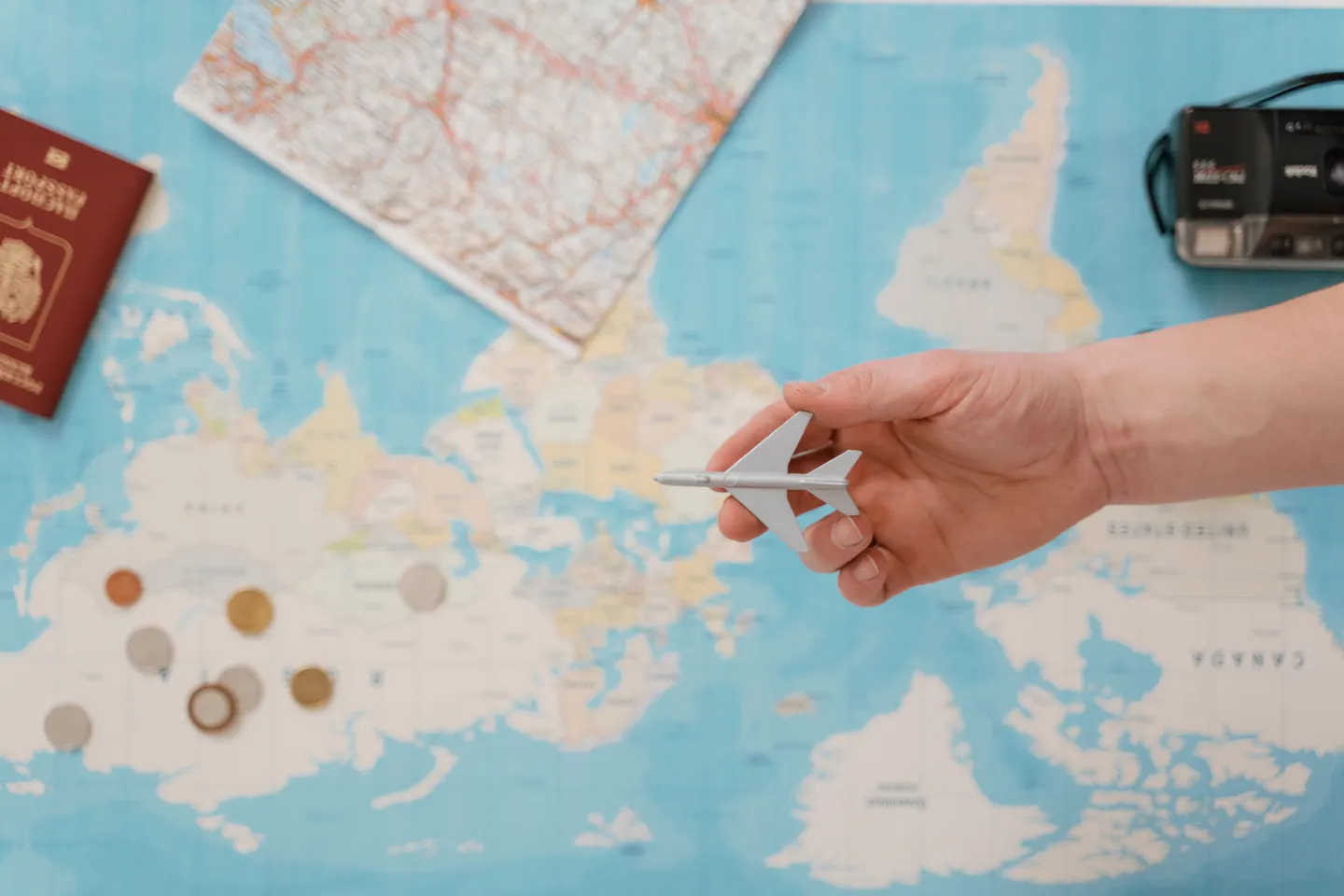 A hand holding a toy airplane above a world map