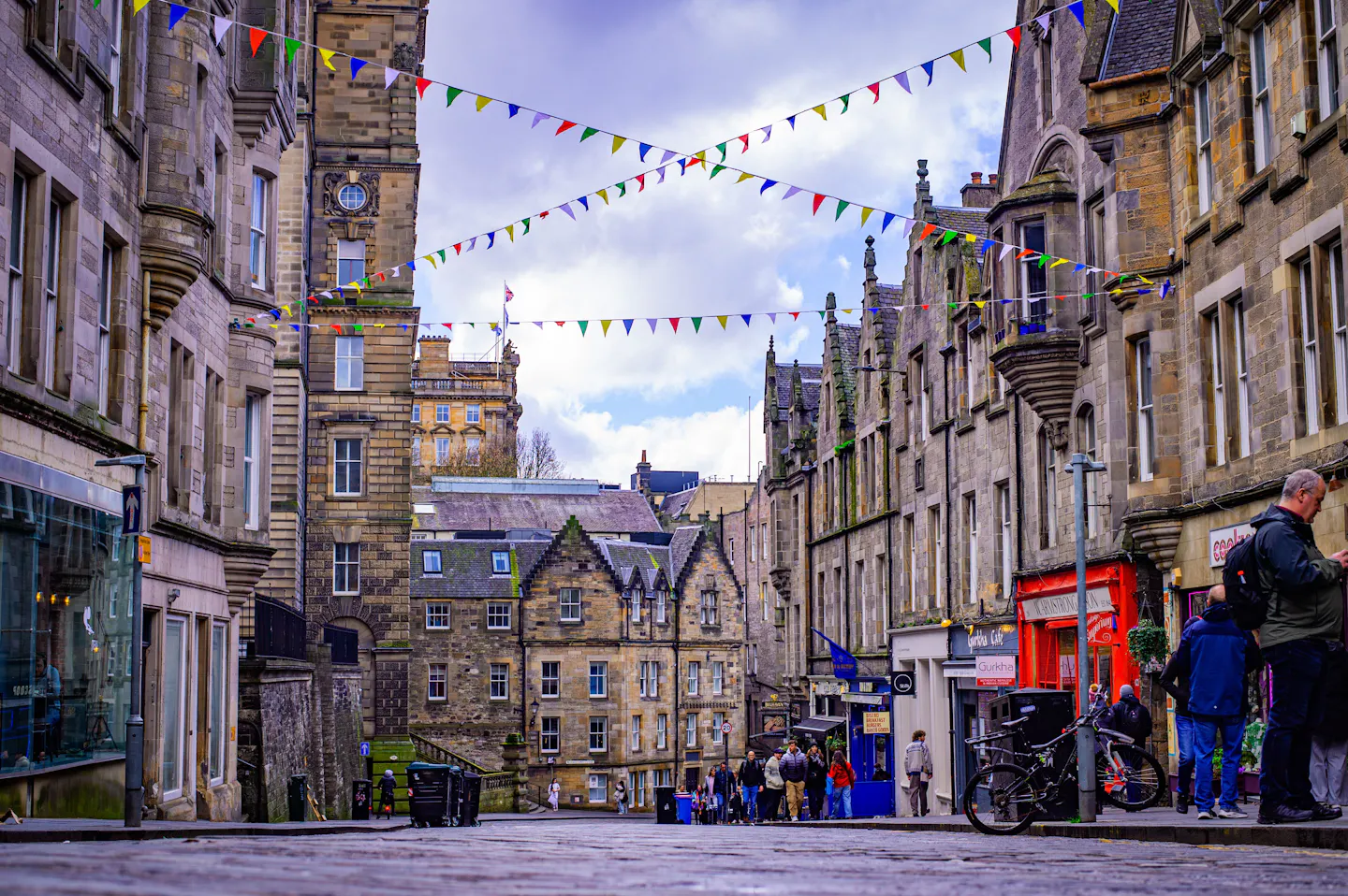 Historic Edinburgh street lined with stone buildings and festival bunting overhead