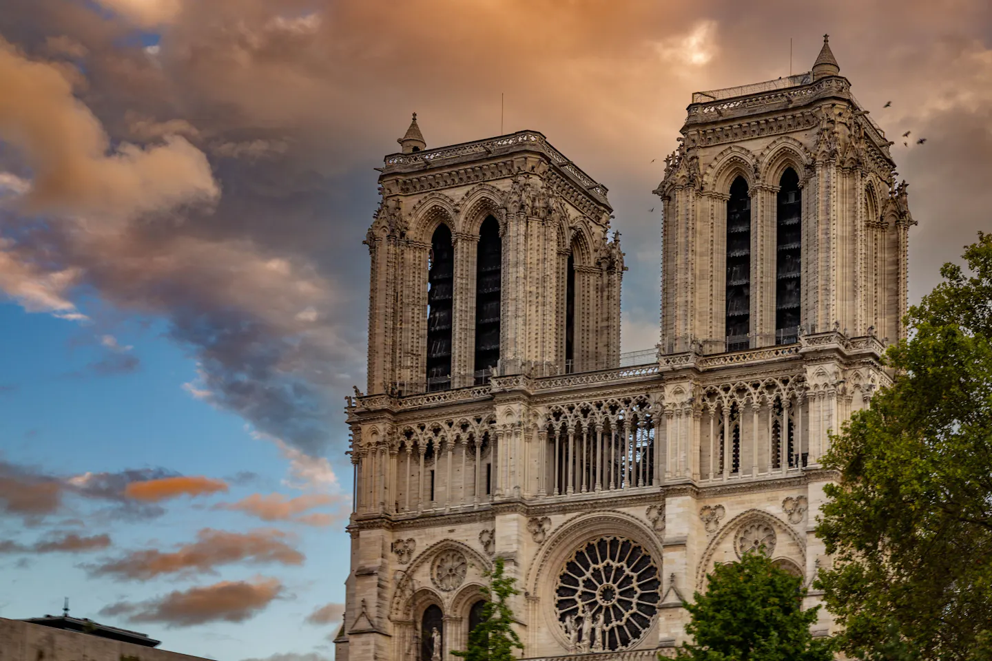 The twin towers and rose window of Notre-Dame cathedral against a golden evening sky