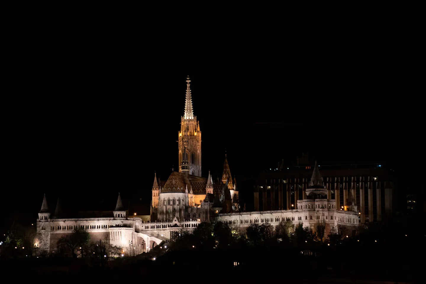 Matthias Church and the white turrets of the Fisherman's Bastion floodlit against a black sky in Budapest