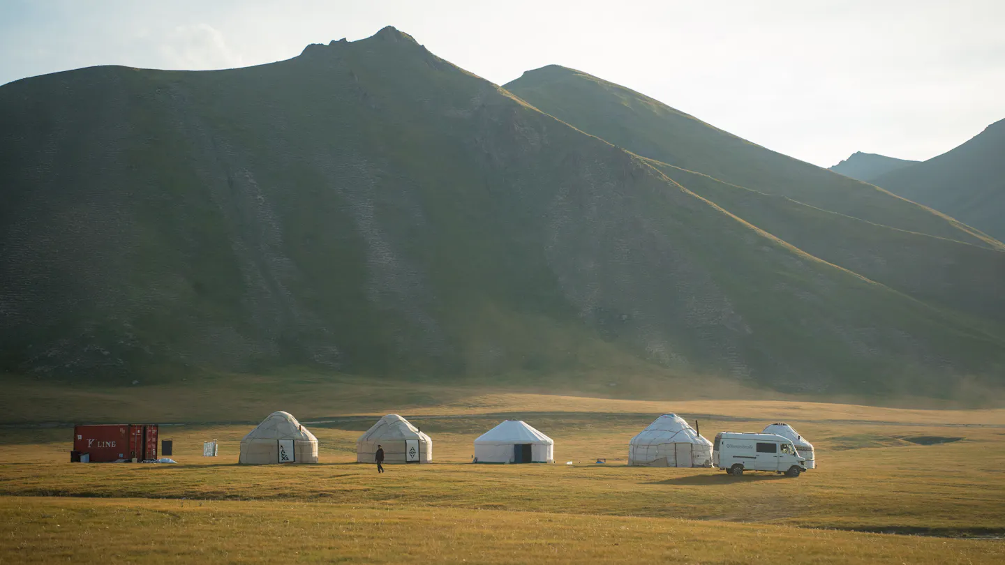 Row of traditional yurts at dawn beneath a mountain range
