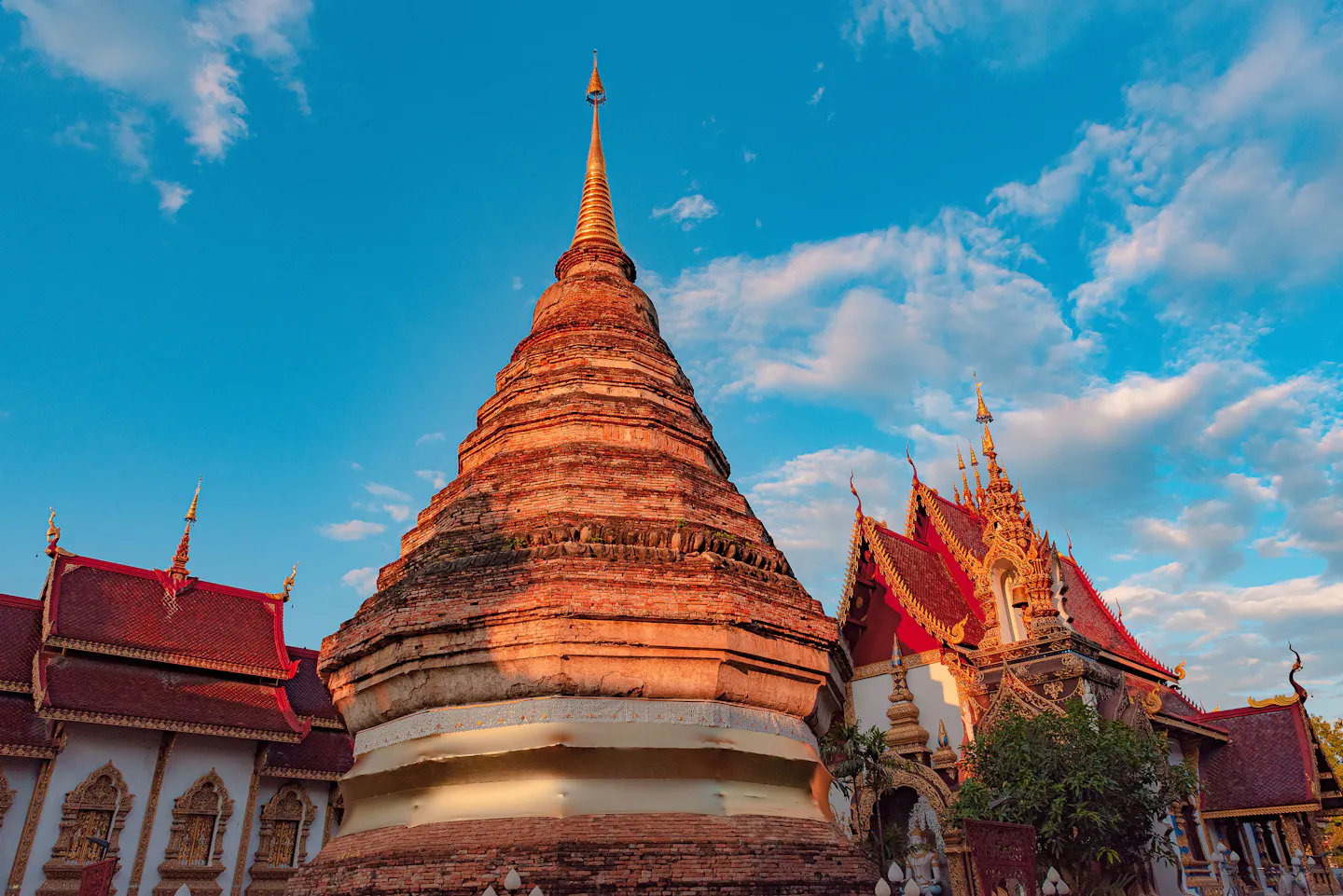 The brick stupa and gilded temple roofs of Wat Chiang Man in Chiang Mai under a blue sky