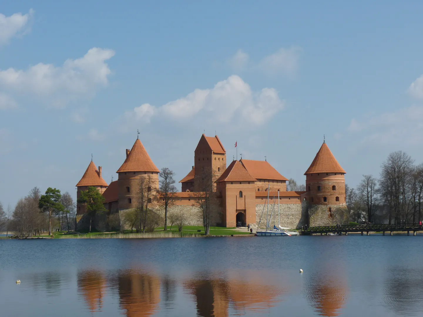 The red brick towers of Trakai Island Castle reflected in the still water of the surrounding lake