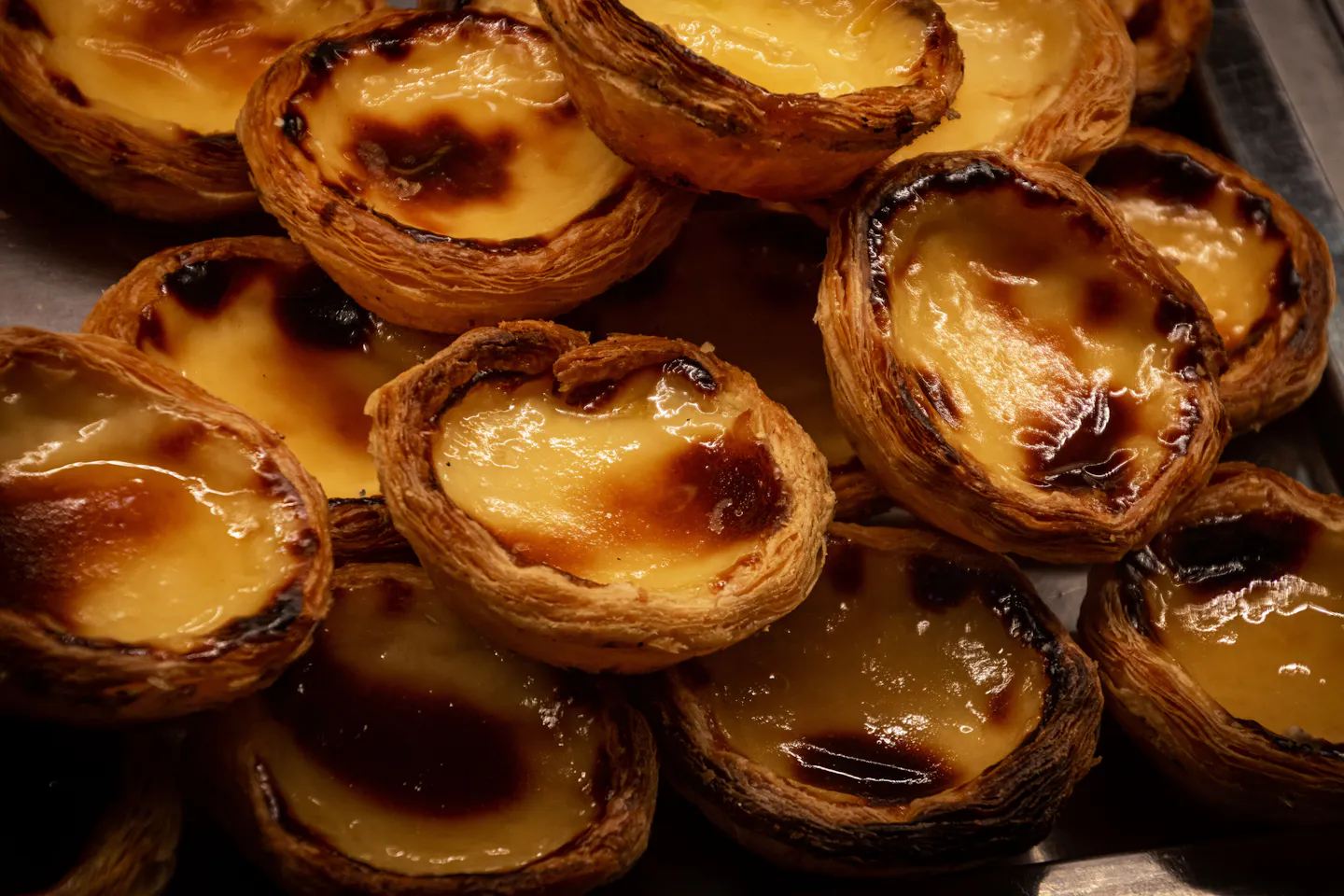 A tray of pasteis de nata with blistered caramelised tops fresh from the oven