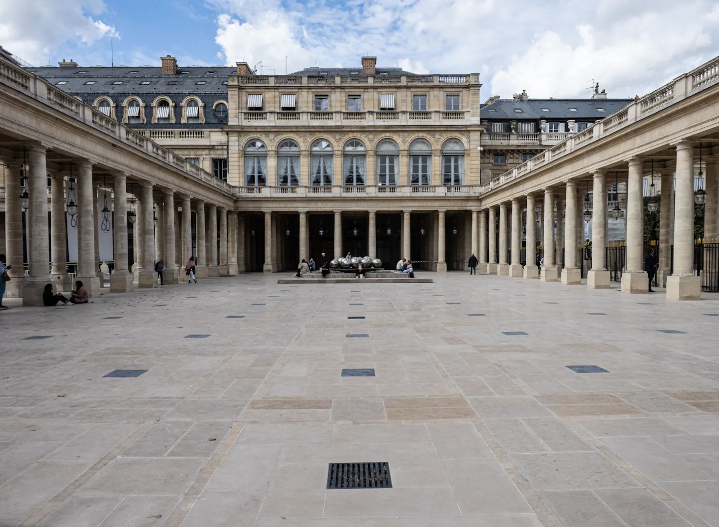The arcaded stone colonnade running around the wide inner courtyard of the Palais-Royal in Paris under a blue sky