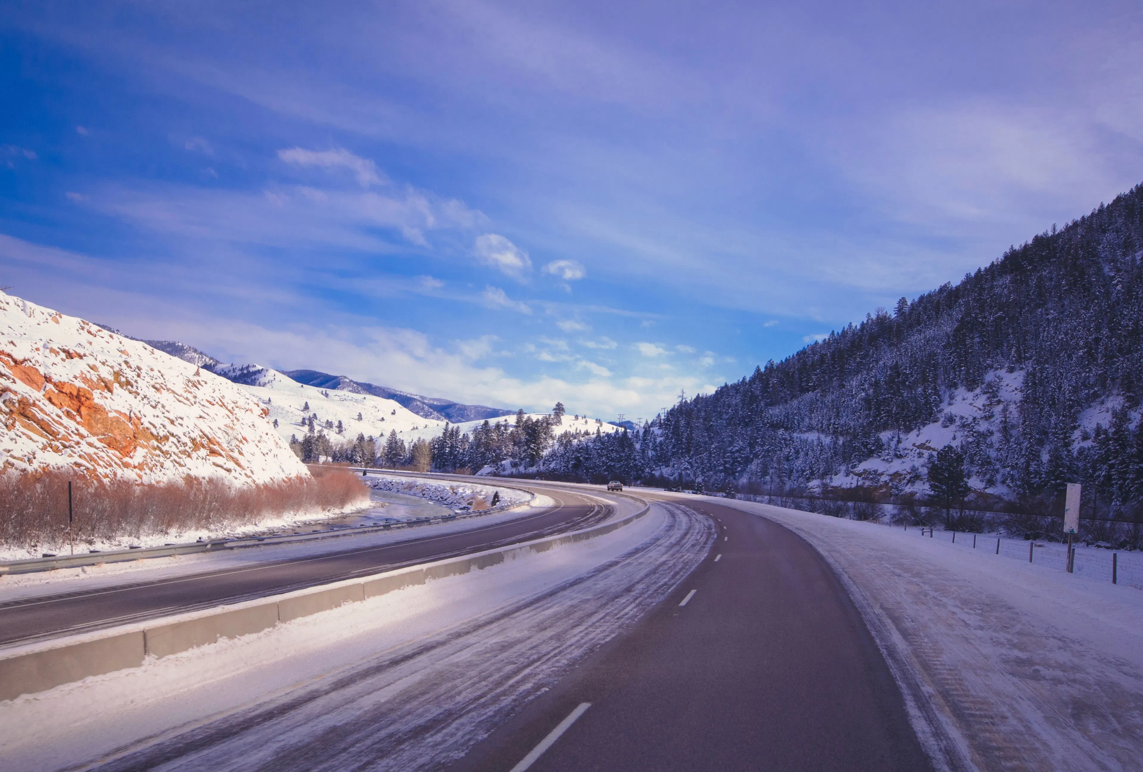 A winter mountain highway winding through snow-covered European-style alpine scenery