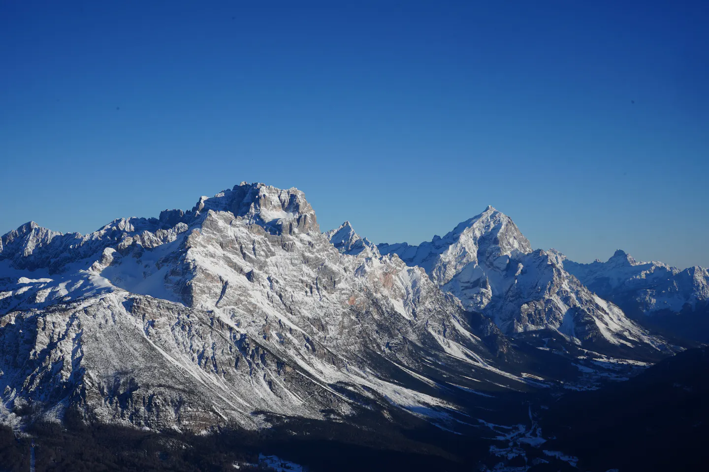 Snow-covered Dolomite peaks above Cortina d'Ampezzo under a deep blue winter sky