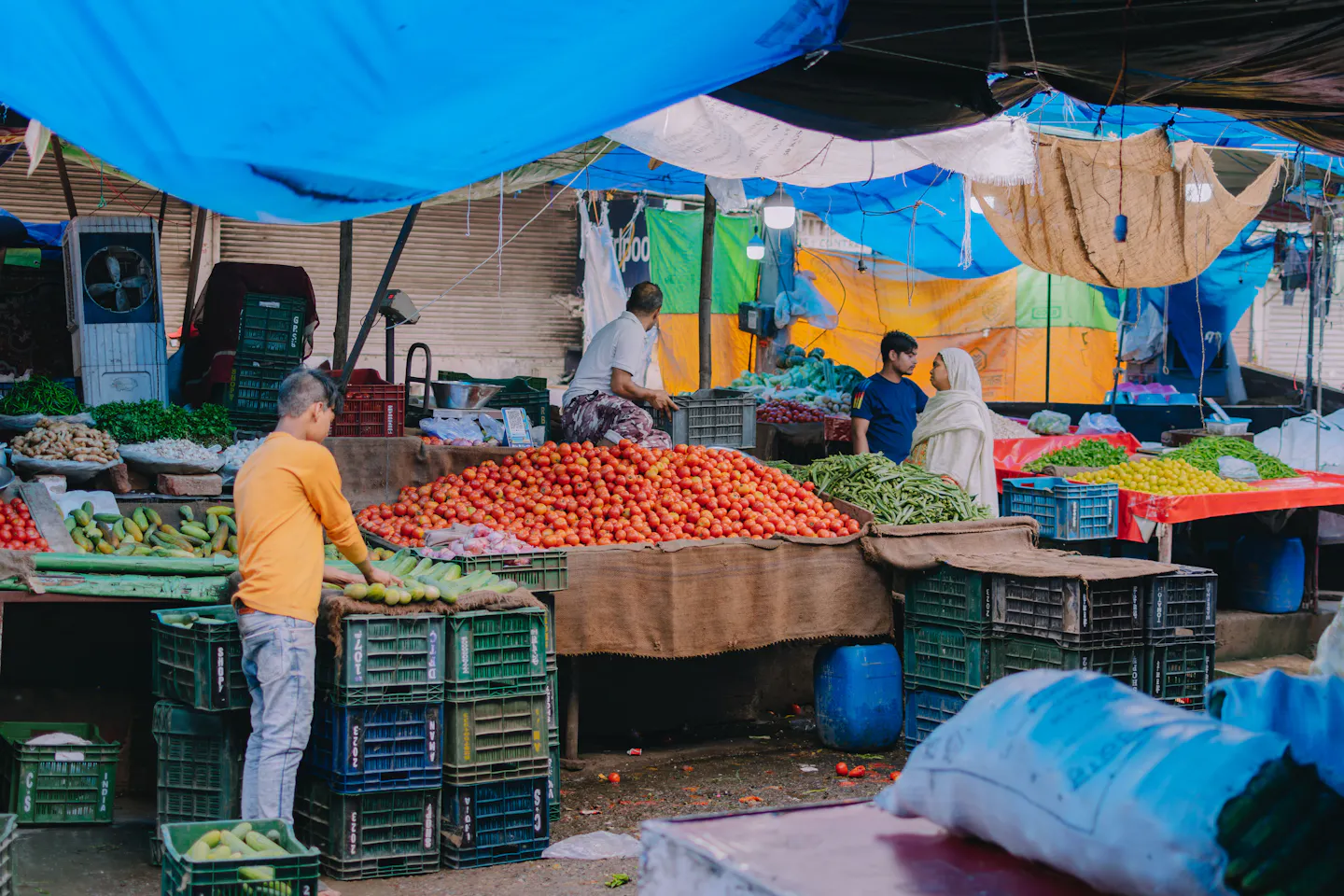 Busy outdoor produce market with vendors and colourful vegetables