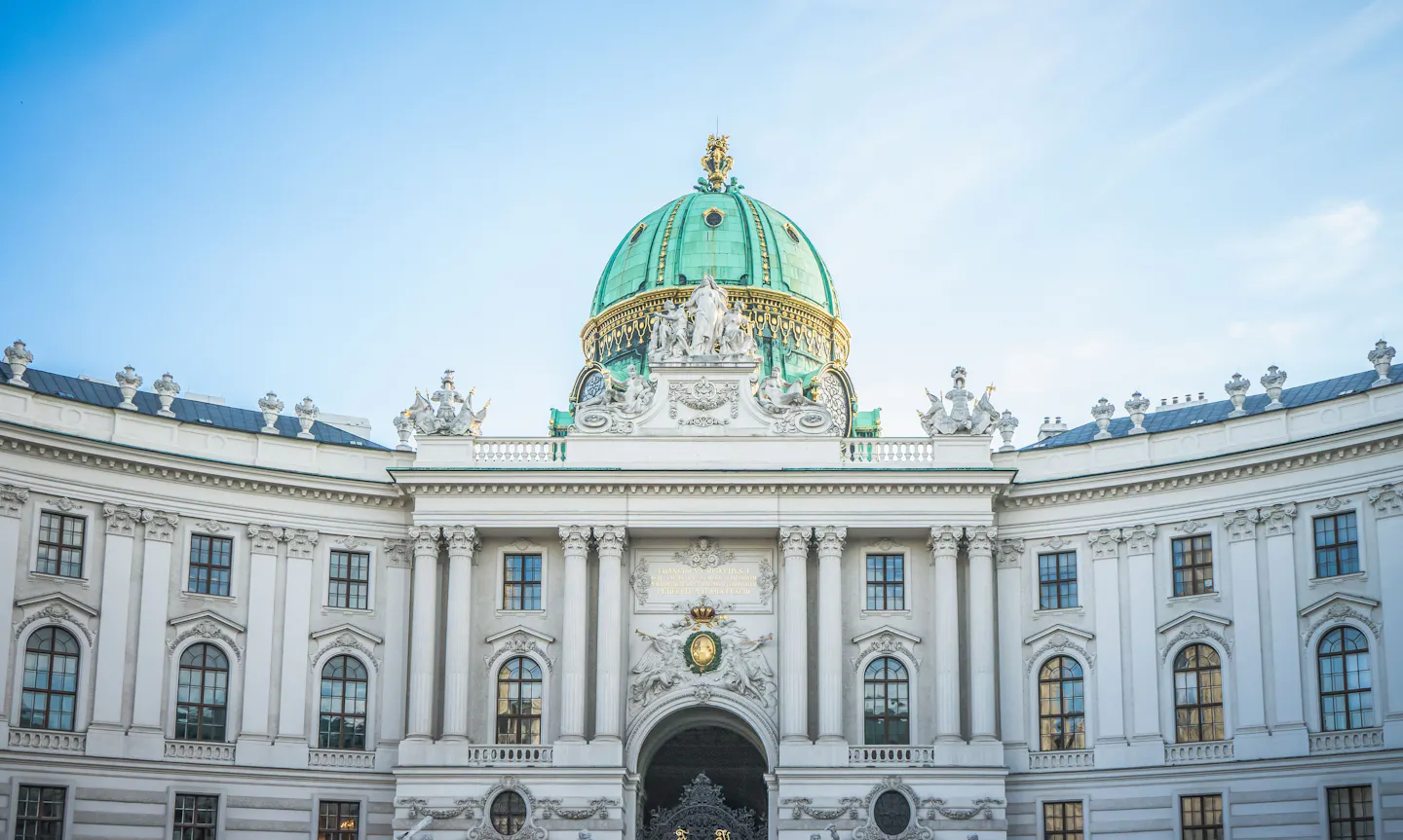 The green copper dome and curved white facade of the Hofburg's St Michael's Wing in Vienna