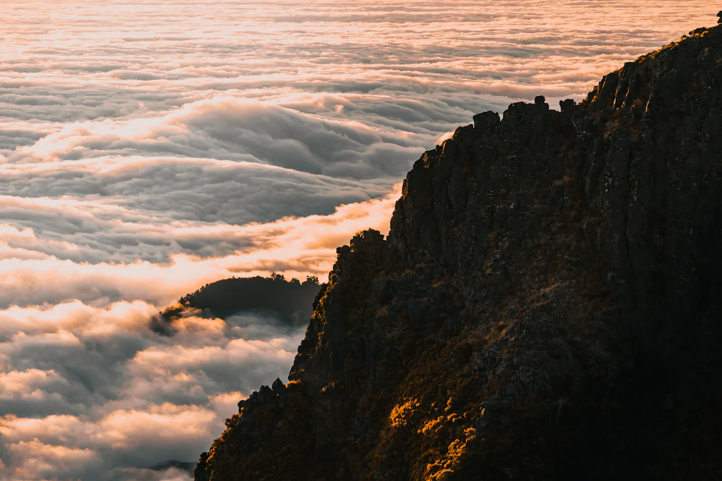 A rocky Madeira ridge catching first light above a sea of cloud at sunrise