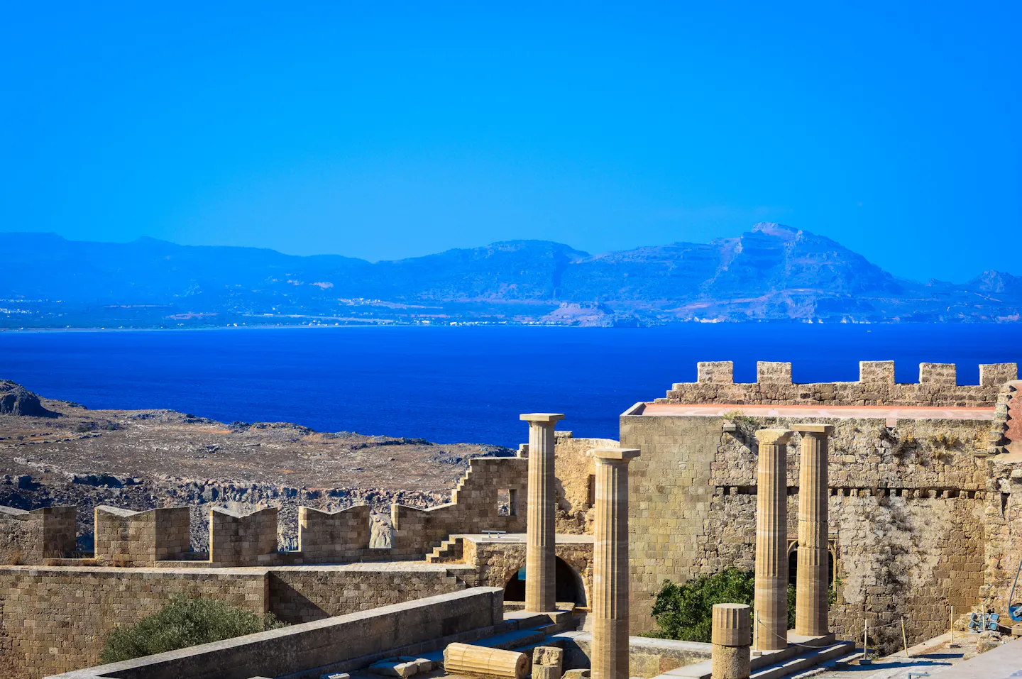 Ancient stone columns on the acropolis above Lindos with the deep blue Aegean beyond