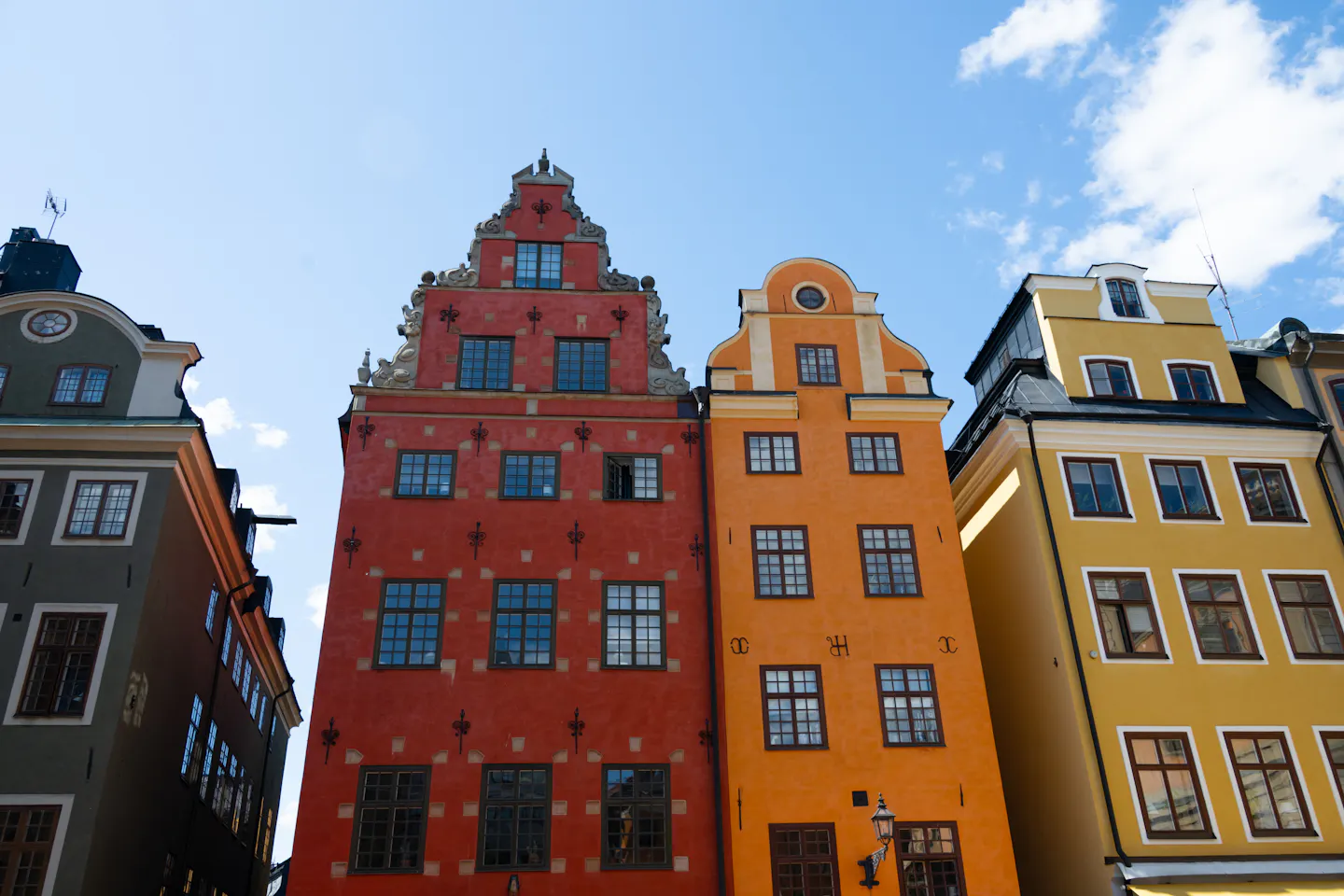 Red, orange and yellow stepped-gable houses on Stortorget square in Stockholm’s old town against a blue sky