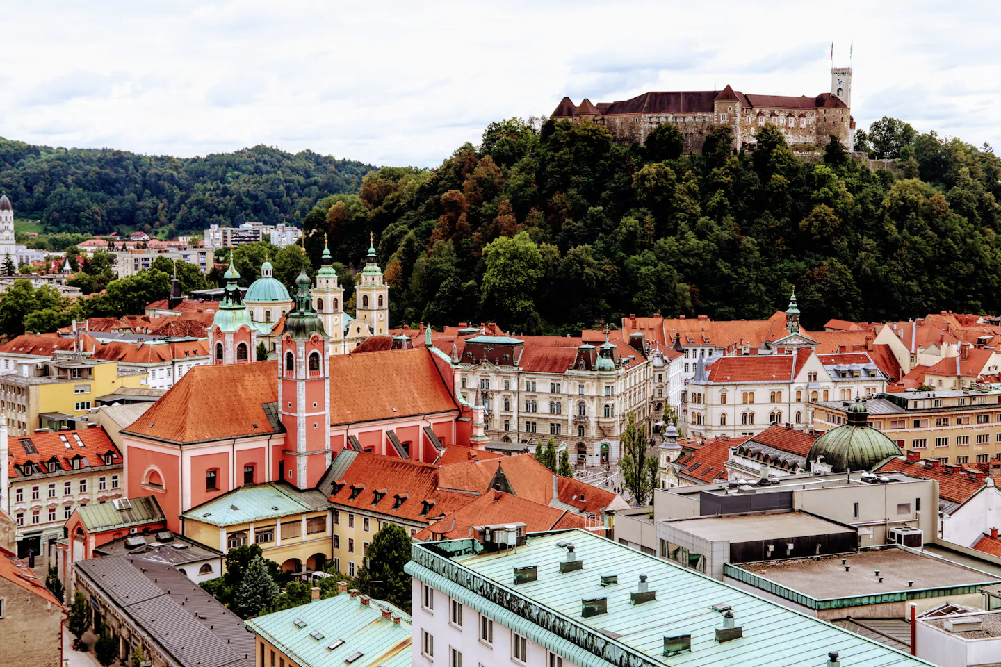 Ljubljana's red-tiled old town rooftops below the castle on its wooded hill