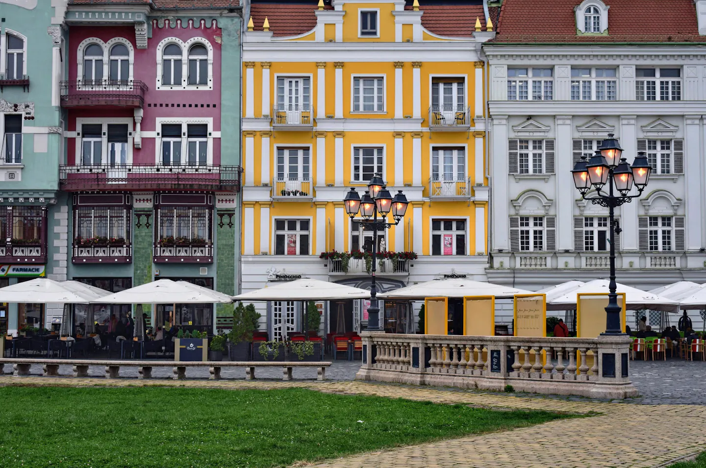 Pink, yellow and green Baroque facades and ornate street lamps on Union Square in Timisoara