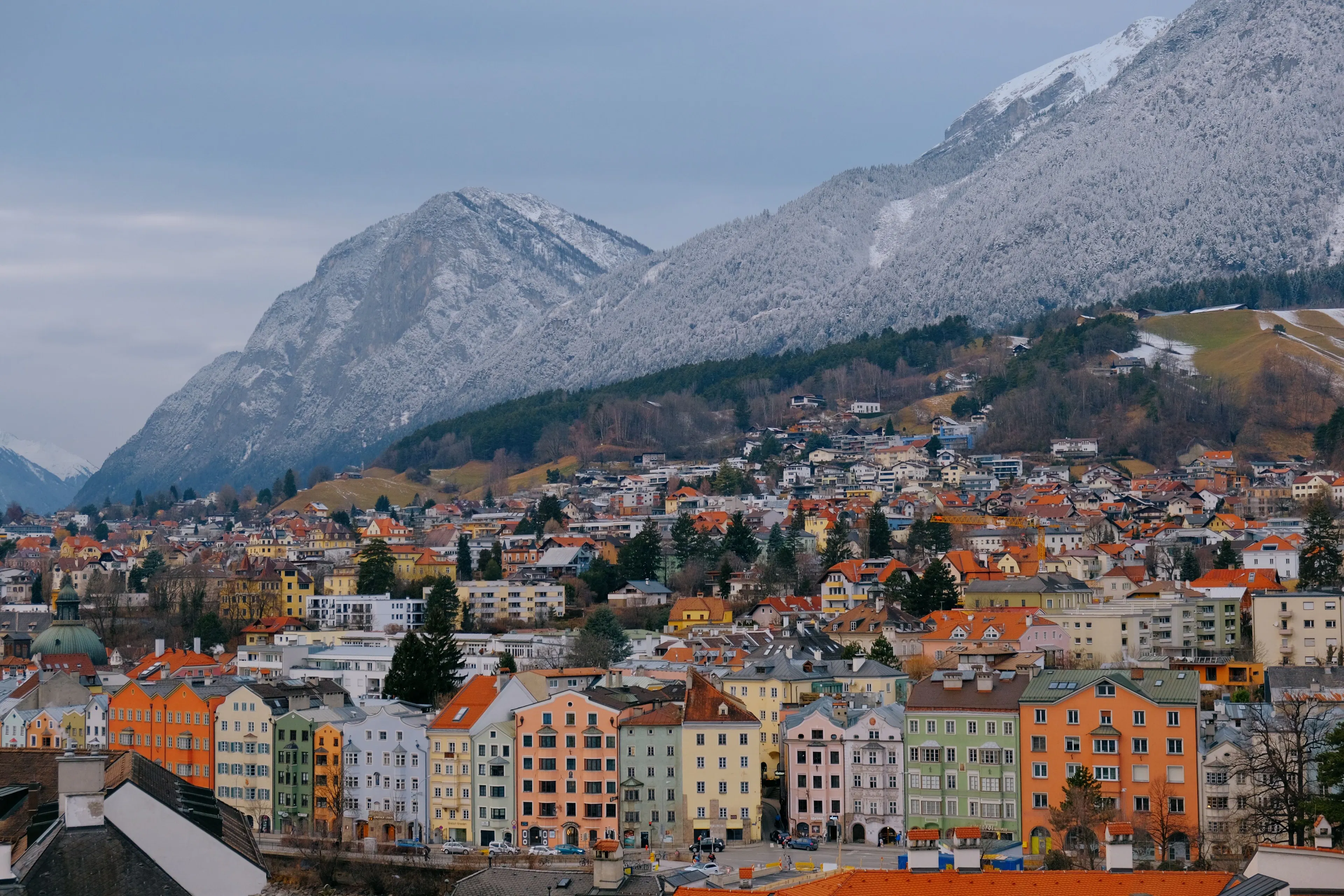 Brightly coloured rooftops of Innsbruck below a vast snow-streaked mountain wall