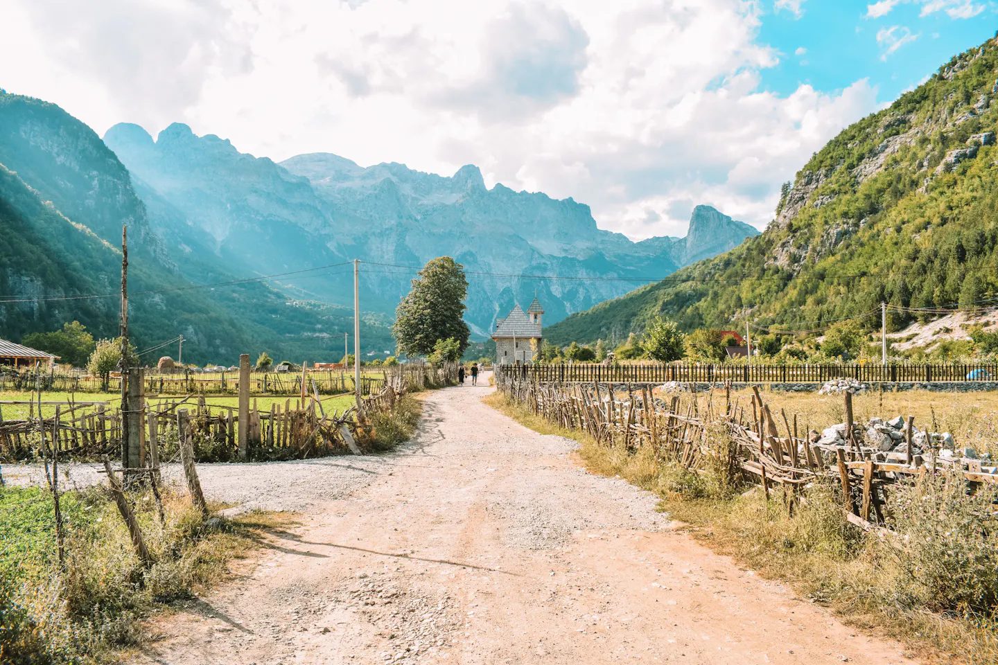 Gravel road running through the Theth valley below the peaks of the Albanian Alps