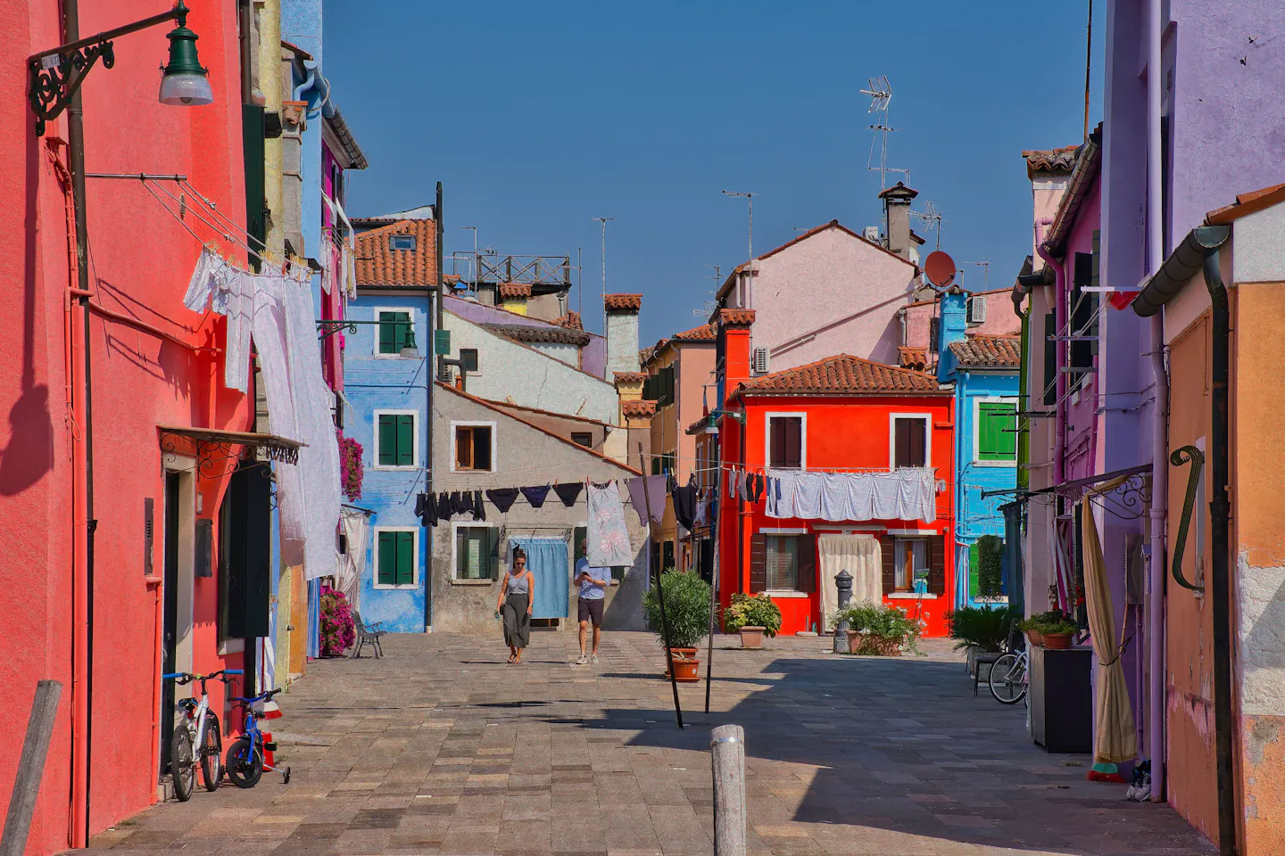 Sunny lane of brightly painted houses in Burano, Venice