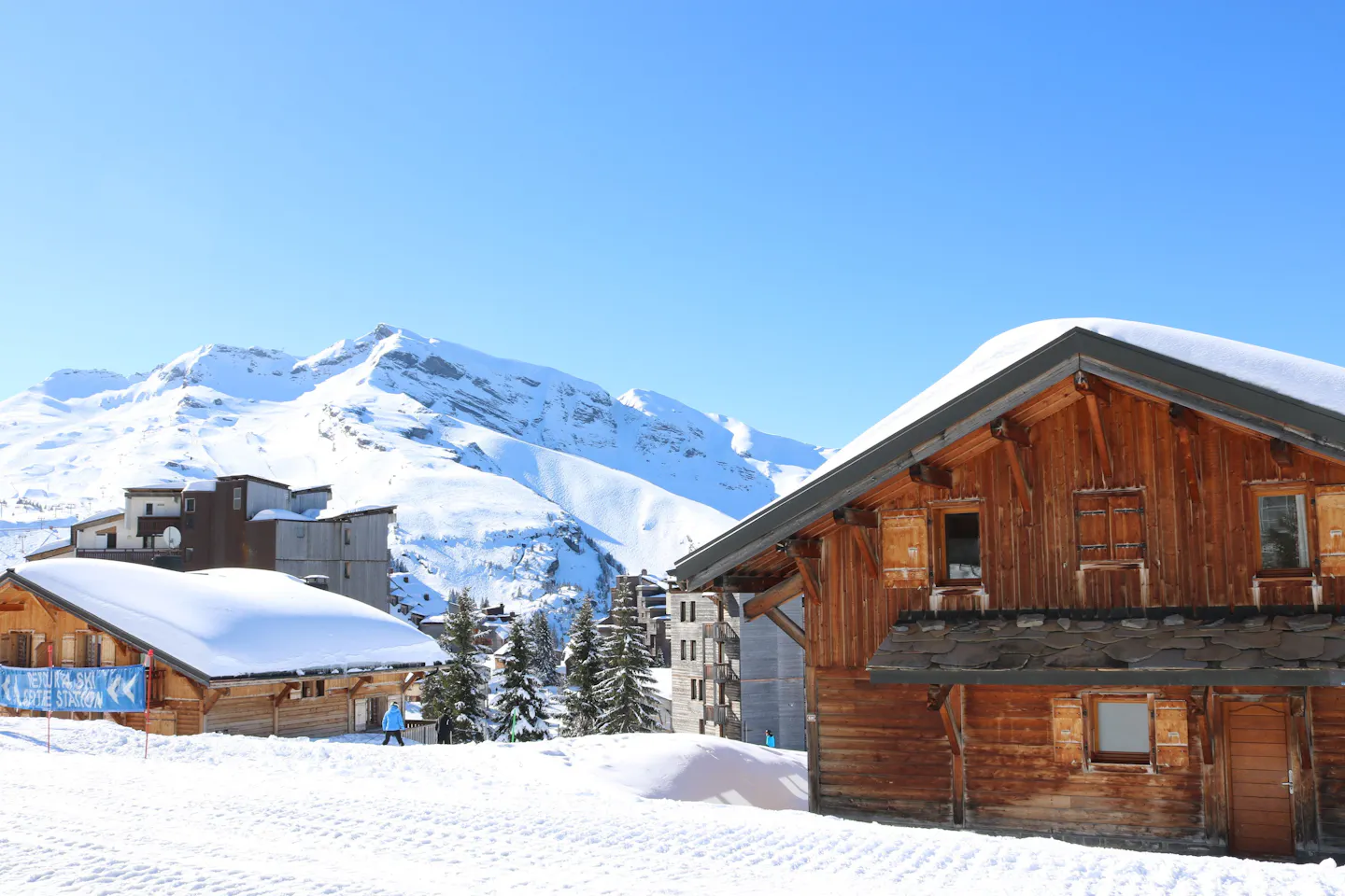 Snow-covered wooden chalets beneath the mountains in Val d’Isère, France