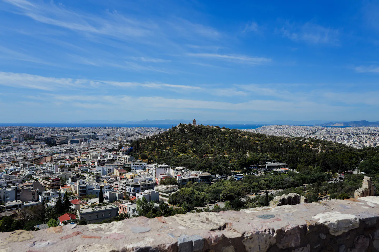 Athens spreading out below the Acropolis towards the wooded Filopappou Hill and the sea