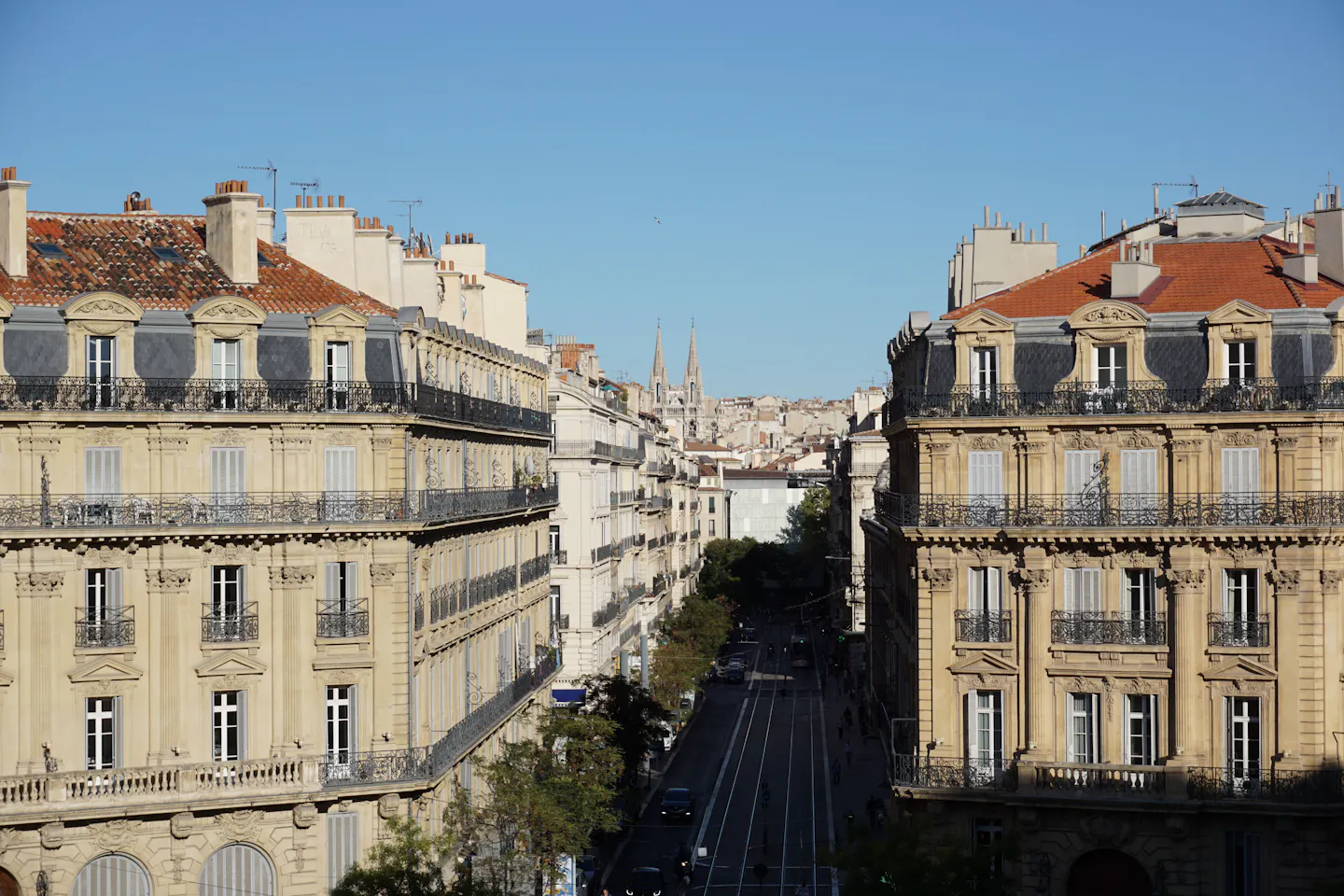 Sunlit boulevard with tram tracks and historic stone buildings in Bordeaux, France