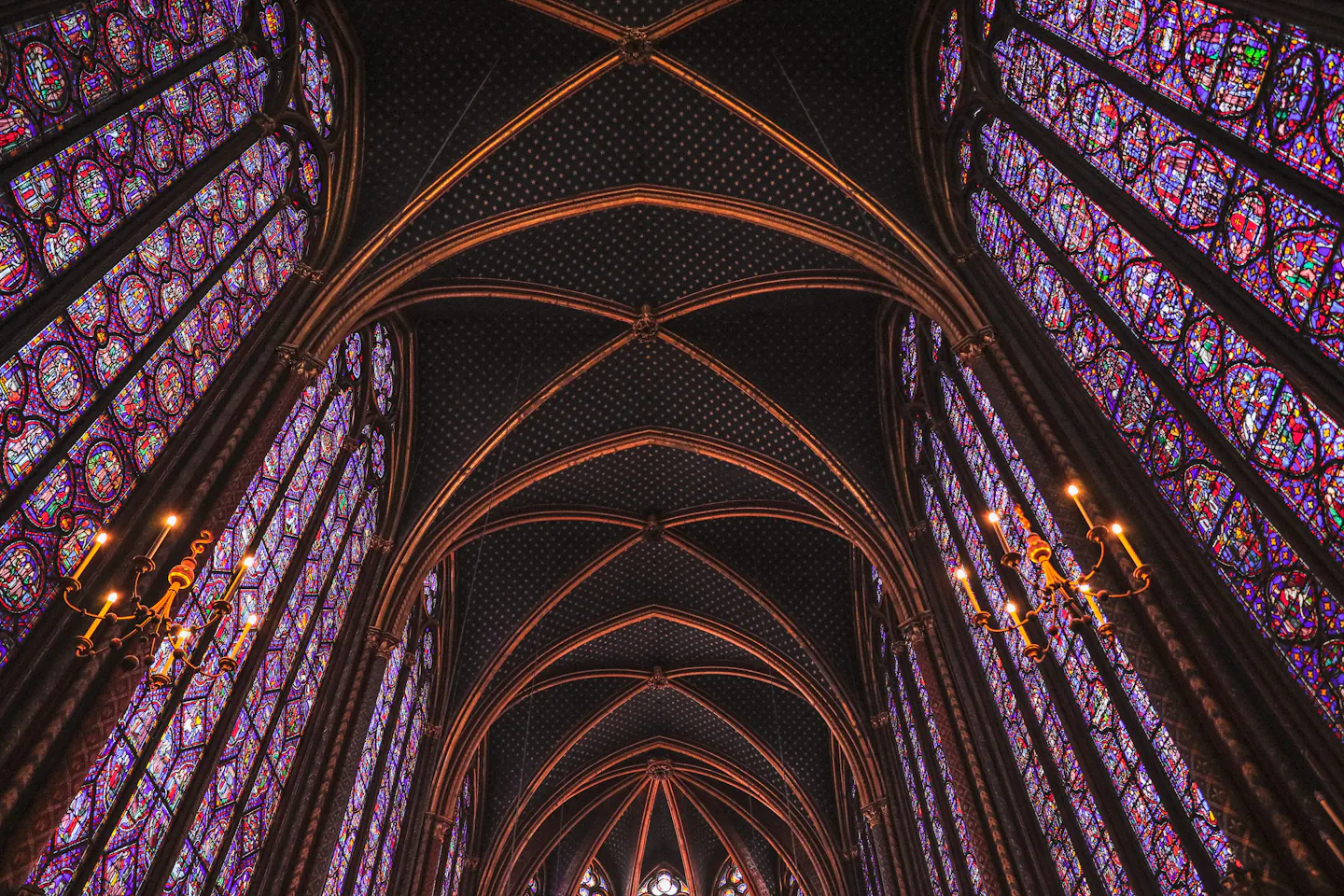 The vaulted ceiling and tall stained-glass windows of the upper chapel at Sainte-Chapelle