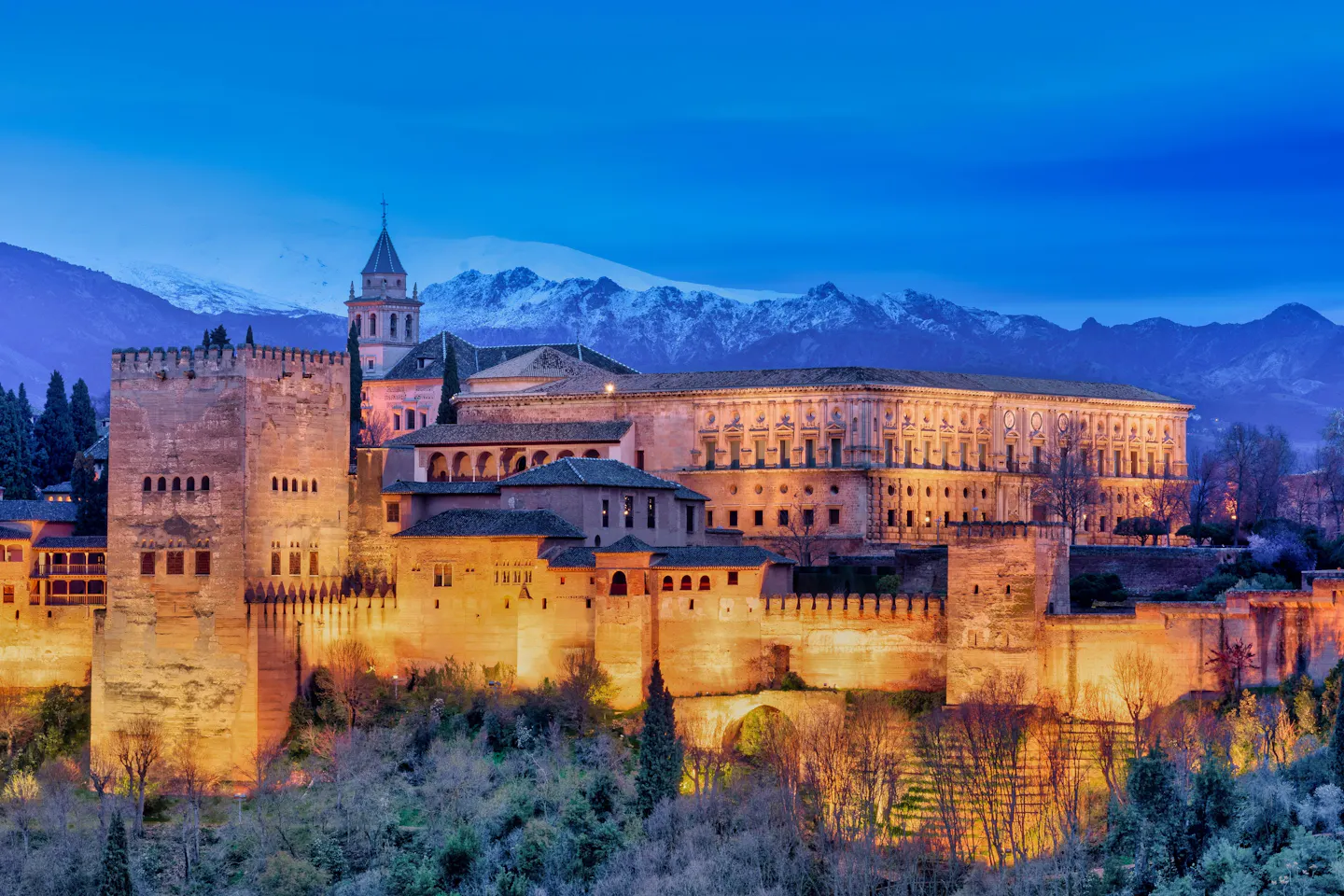 Granada’s Alhambra glowing at dusk beneath the snowy Sierra Nevada