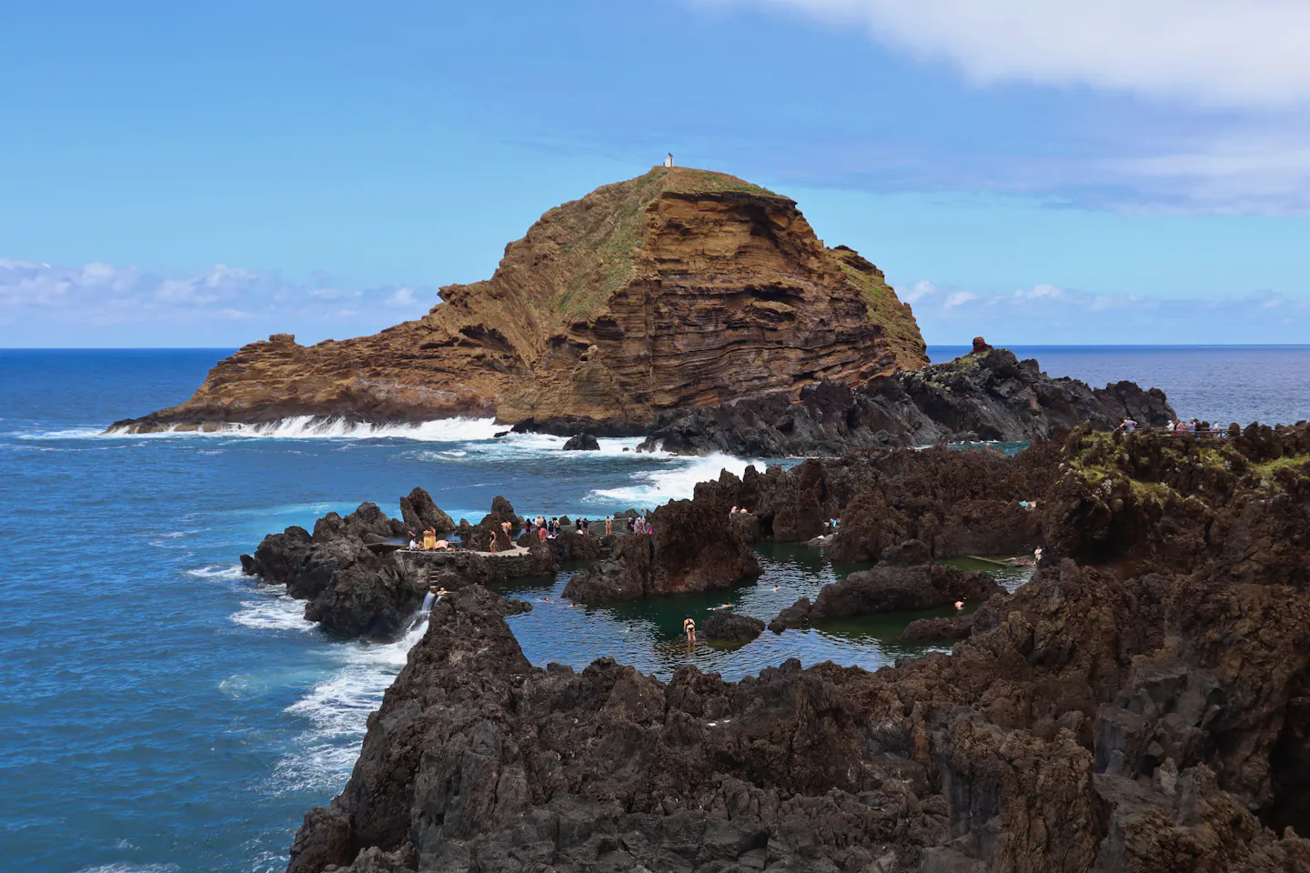 Volcanic rock pools at Porto Moniz on Madeira below a headland and the open Atlantic