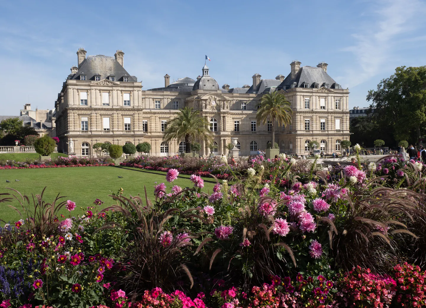 Flower beds in full bloom in front of the Luxembourg Palace under a clear blue sky
