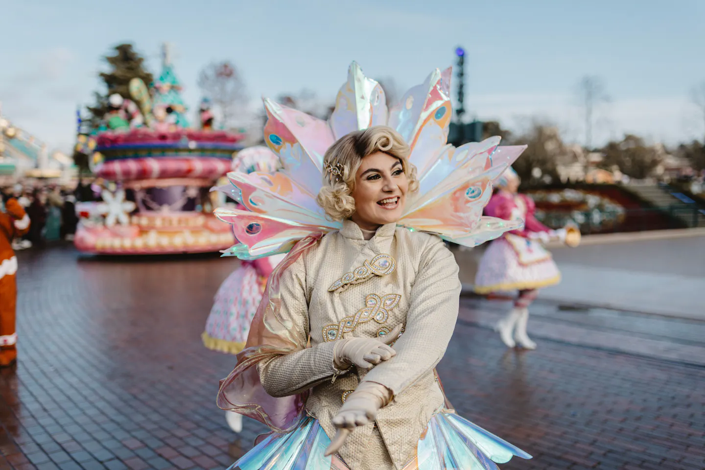 Costumed performer in a Christmas parade at Disneyland Paris, with a festive float behind her