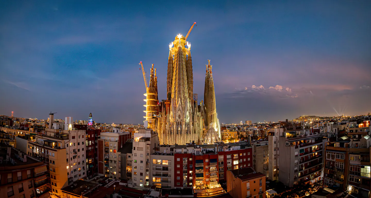 The Sagrada Familia lit up at twilight above the rooftops of Barcelona's Eixample