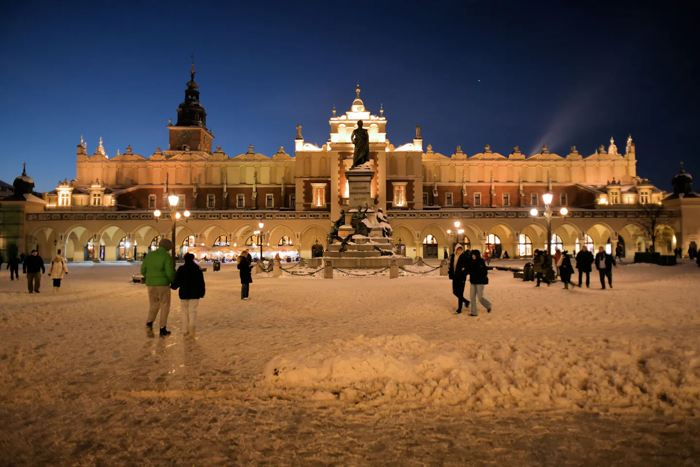 Snow-covered Main Market Square and Cloth Hall glowing at night in Kraków, Poland