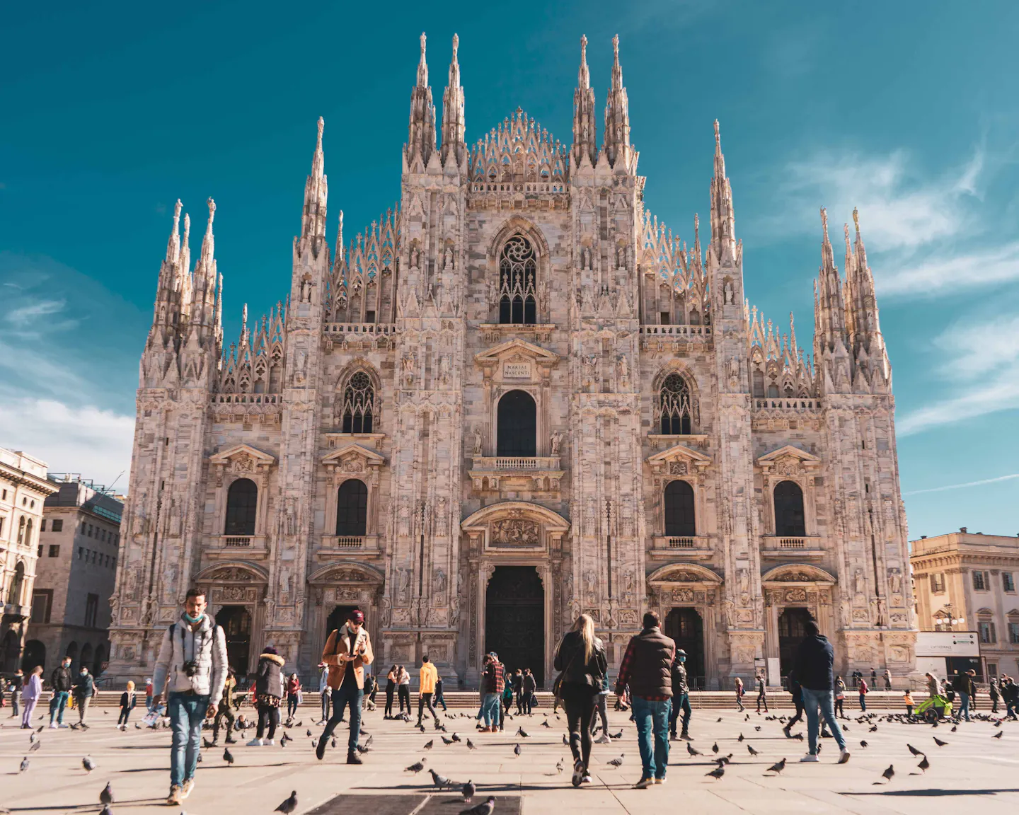 Visitors in the piazza in front of the Gothic facade of Milan Cathedral