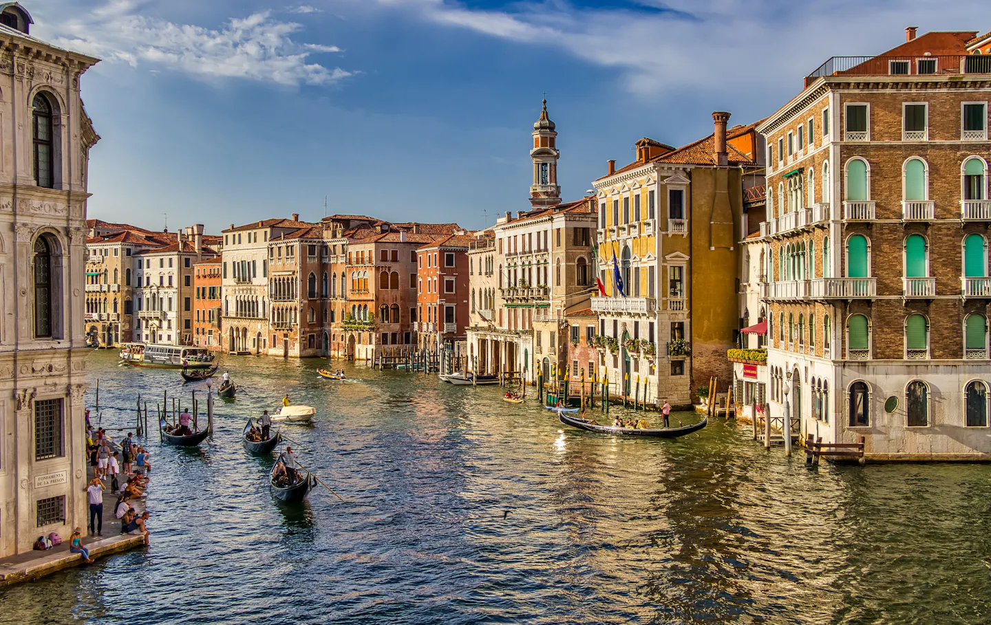 Venice's Grand Canal lined with historic palazzi and gondolas on a bright day