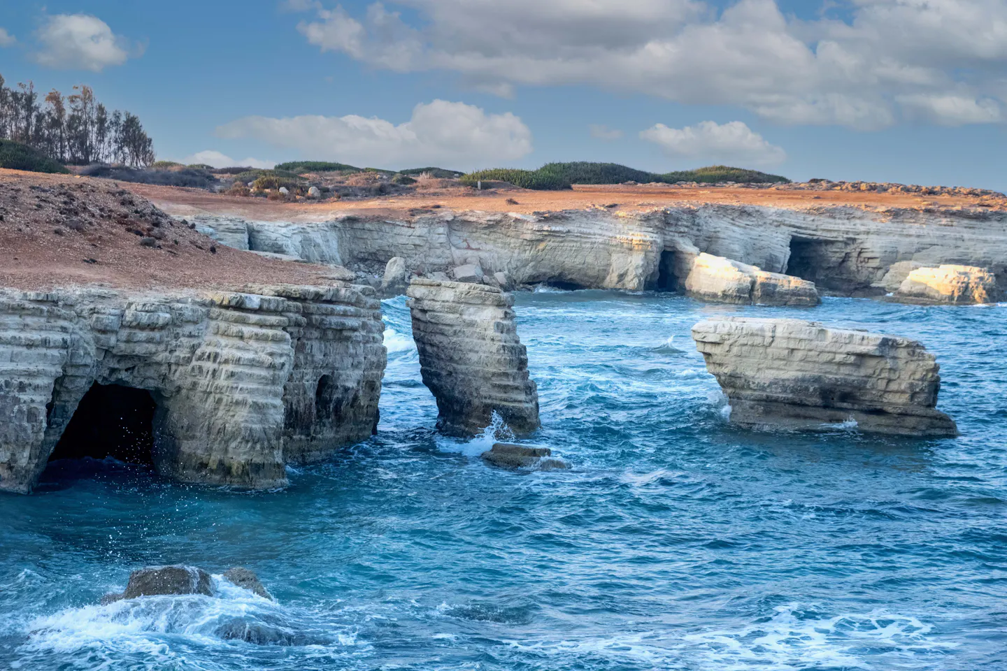 Limestone sea caves and stacks above clear turquoise water on the coast of Cyprus