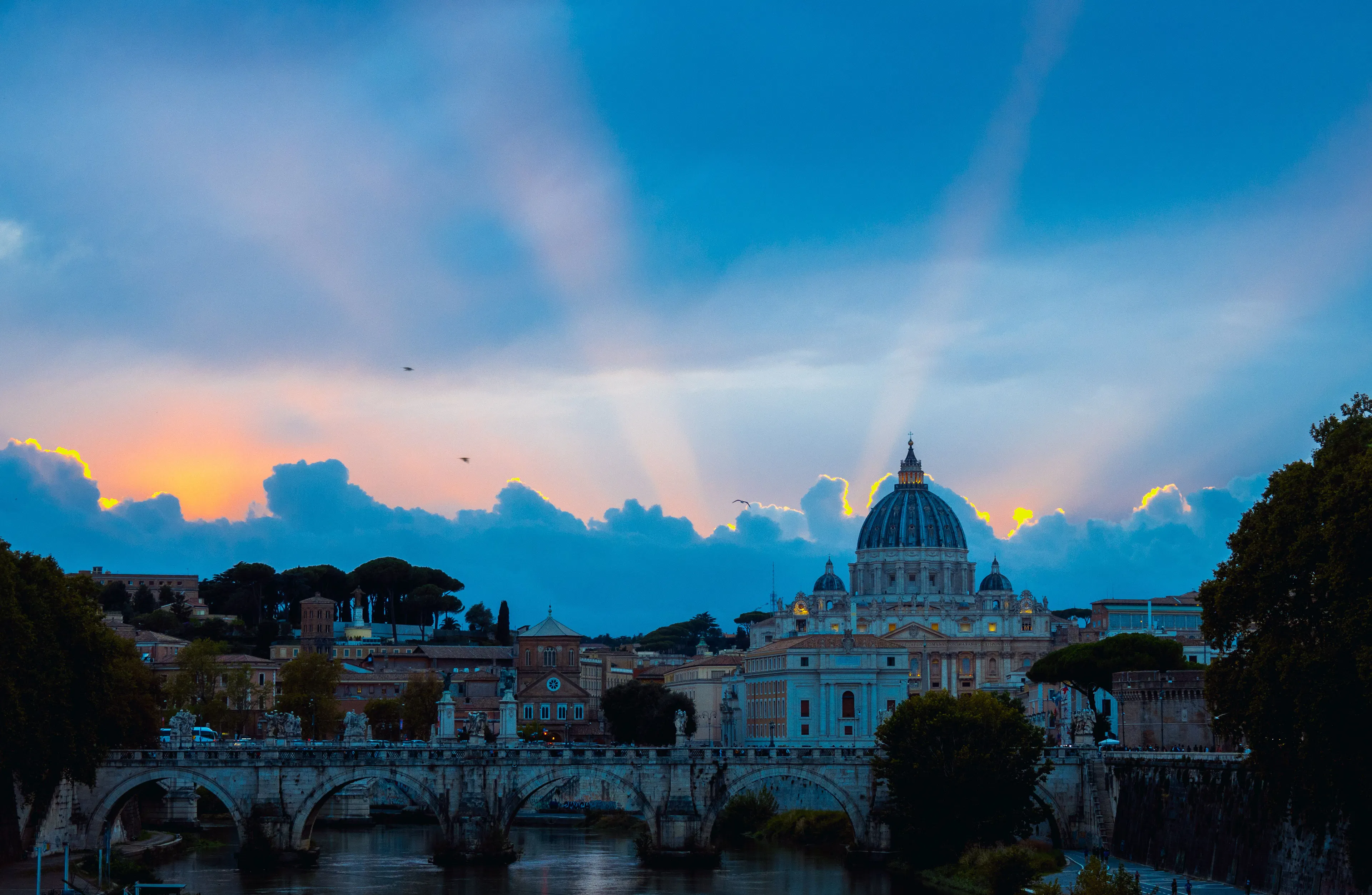 The dome of St Peter's Basilica above the Tiber and Ponte Sant'Angelo in Rome at dusk